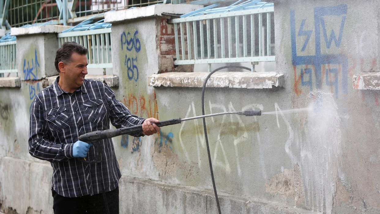 Sofia, Bulgariq - September 12, 2014: A cleaner is cleaning graffiti from the outer side of a wall of a school in Sofia.