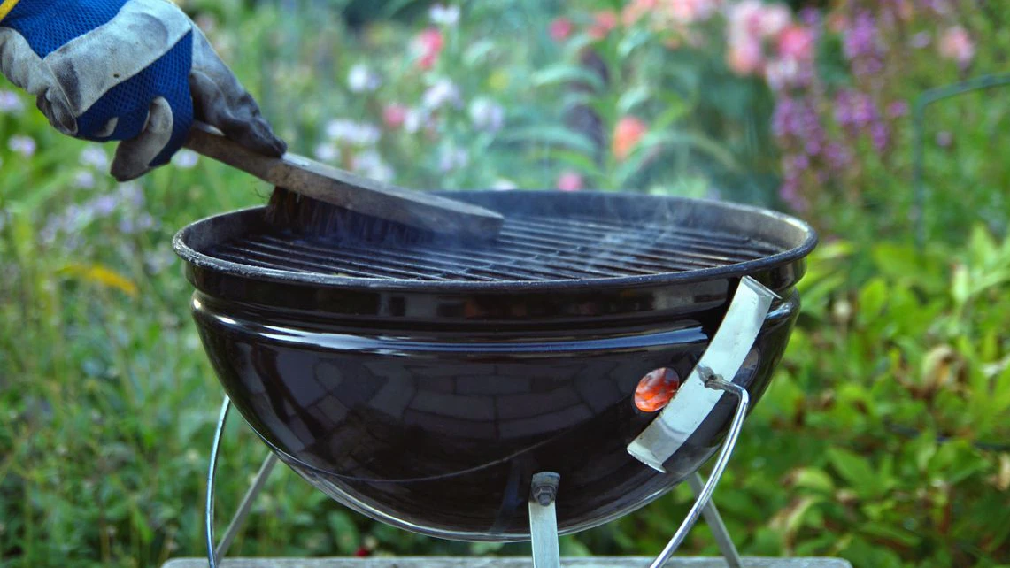 man is cleaning a grill at garden