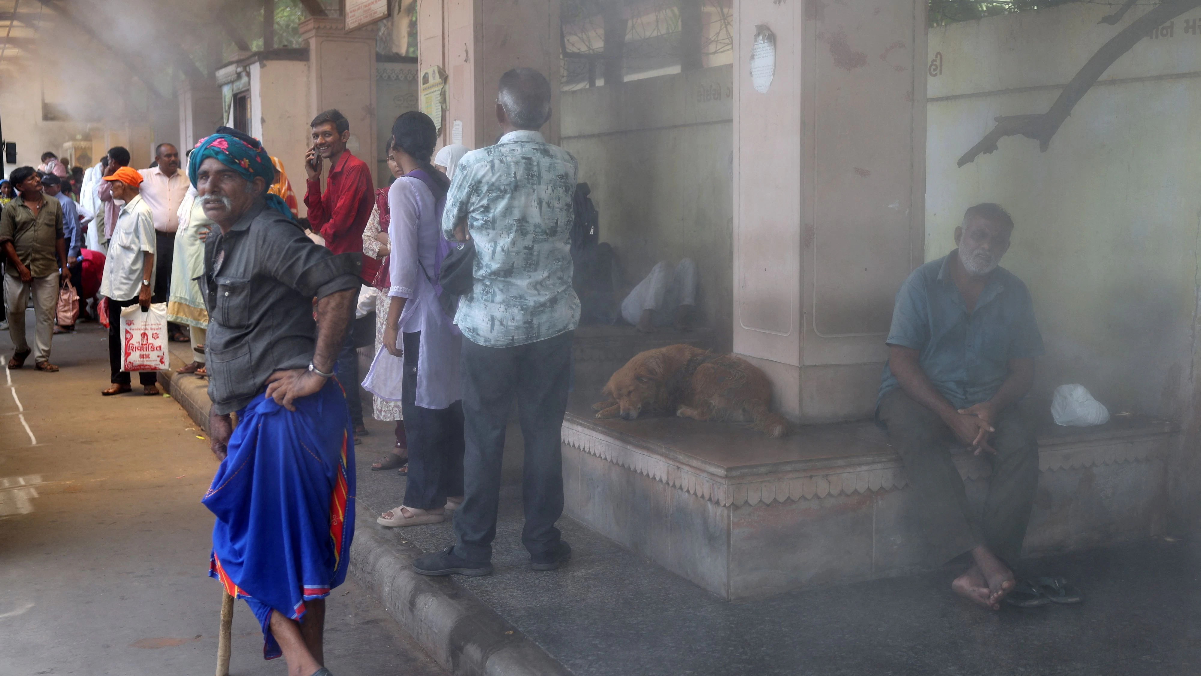 Passengers wait at a bus stop equipped with water mist to provide relief from heat in Ahmedabad, India, June 5, 2026.  REUTERS/Amit Dave