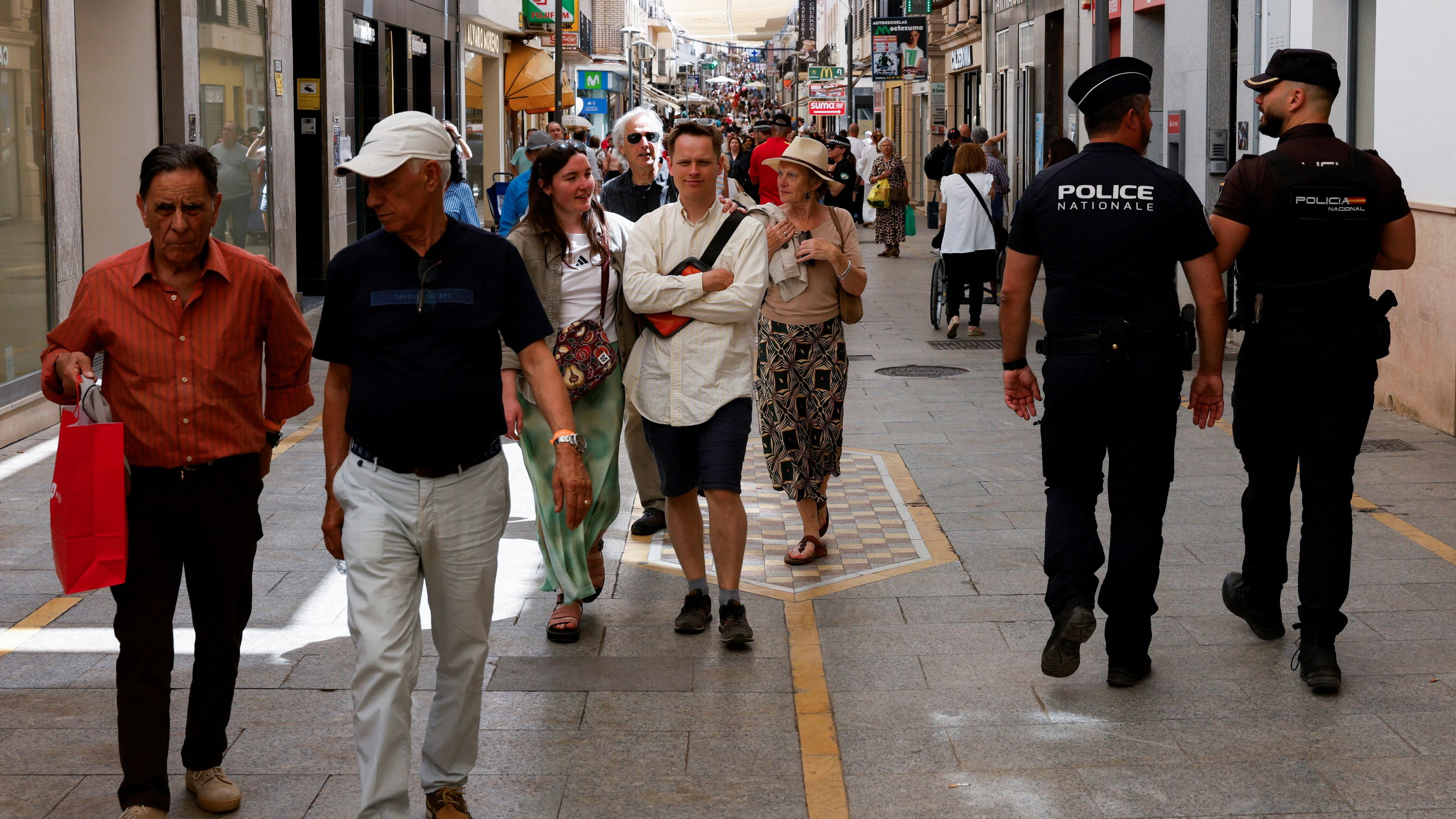 A French police officer and a Spanish national police officer walk past tourists as they patrol a shopping street, during the European Police Stations project, which allows the international exchange of officers to form mixed patrols in destinations with high tourist traffic, in downtown Ronda, southern Spain, May 20, 2026. REUTERS/Jon Nazca