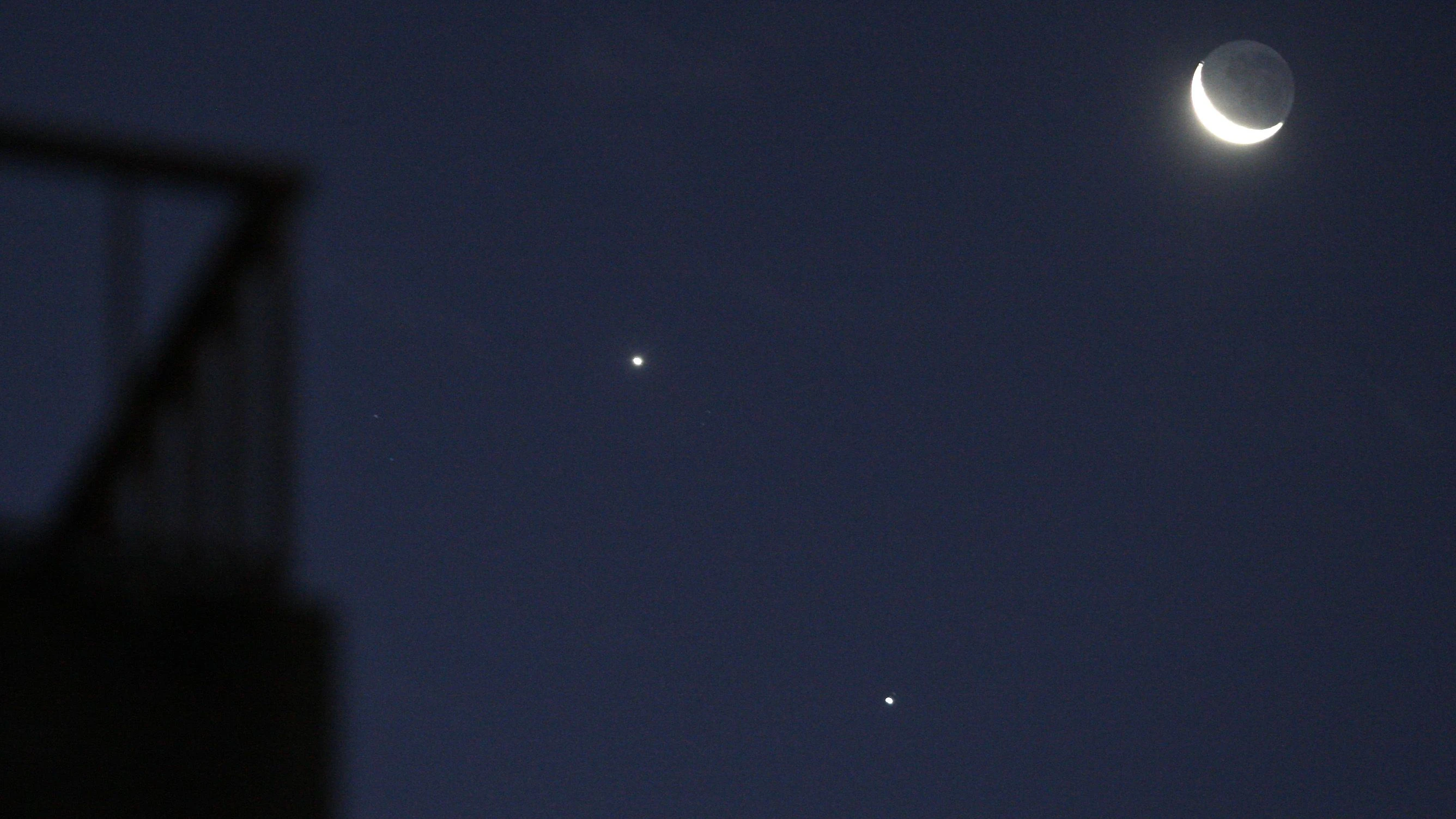 A crescent moon and the planets Jupiter (bottom) and Venus are seen in the sky over Buenos Aires December 1, 2008. Astronomers and skygazers across the world are keeping watch on Monday night for a rare astronomical phenomenon as two of the brightest naked-eye planets, Venus and Jupiter, join a thin crescent moon to create a brief "unhappy face" in the sky.   REUTERS/Enrique Marcarian (ARGENTINA)