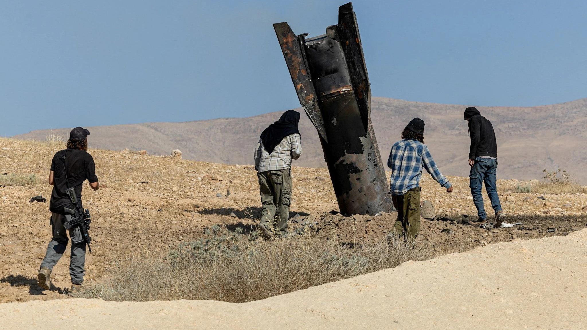Israeli settlers stand next to part of a missile protruding from the ground, following strikes from Iran, in the central Israeli-occupied West Bank, June 8, 2026. REUTERS/Naama Stern ISRAEL OUT. NO COMMERCIAL OR EDITORIAL SALES IN ISRAEL     TPX IMAGES OF THE DAY     