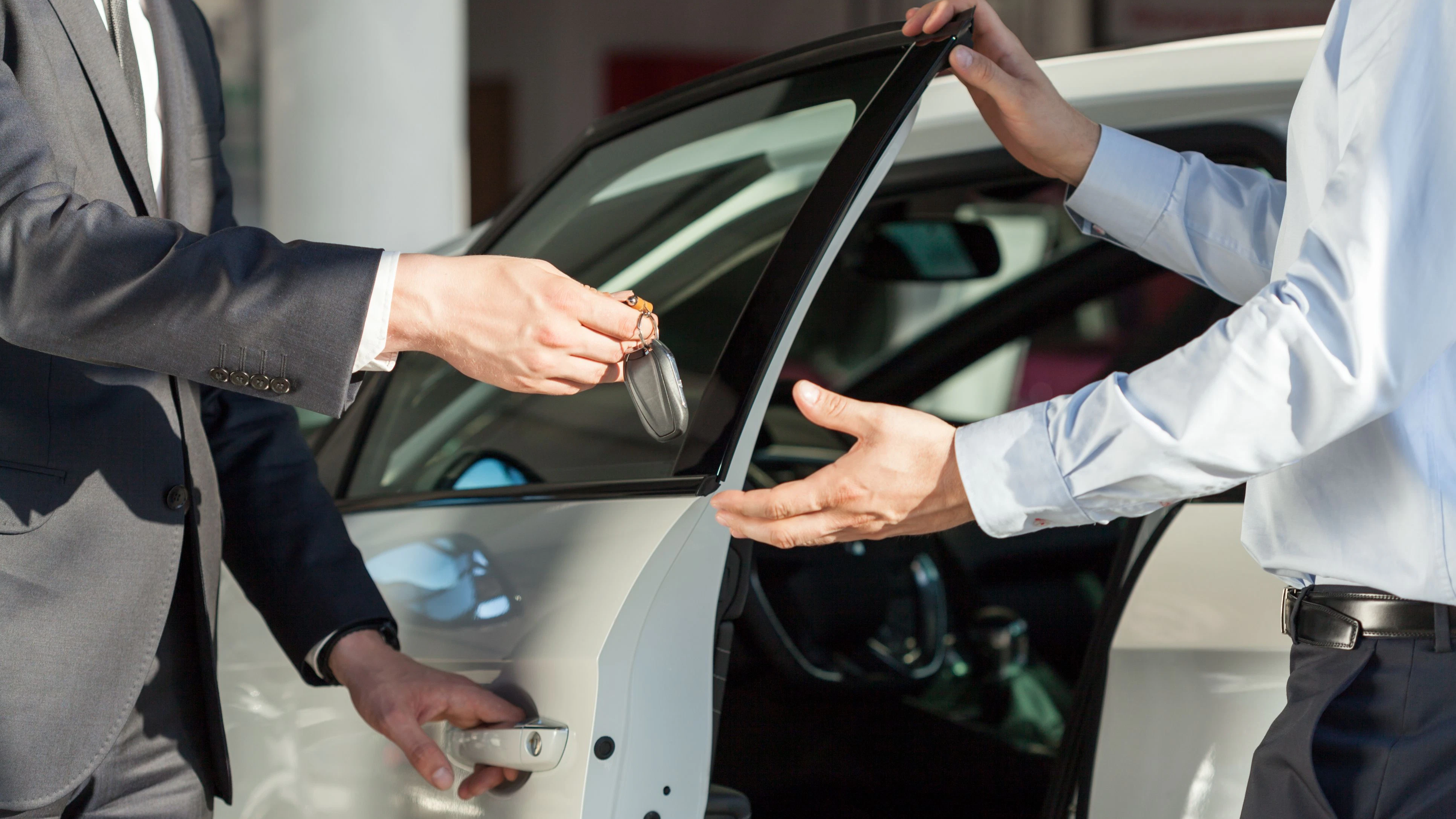 Salesman's hands giving key to male customer