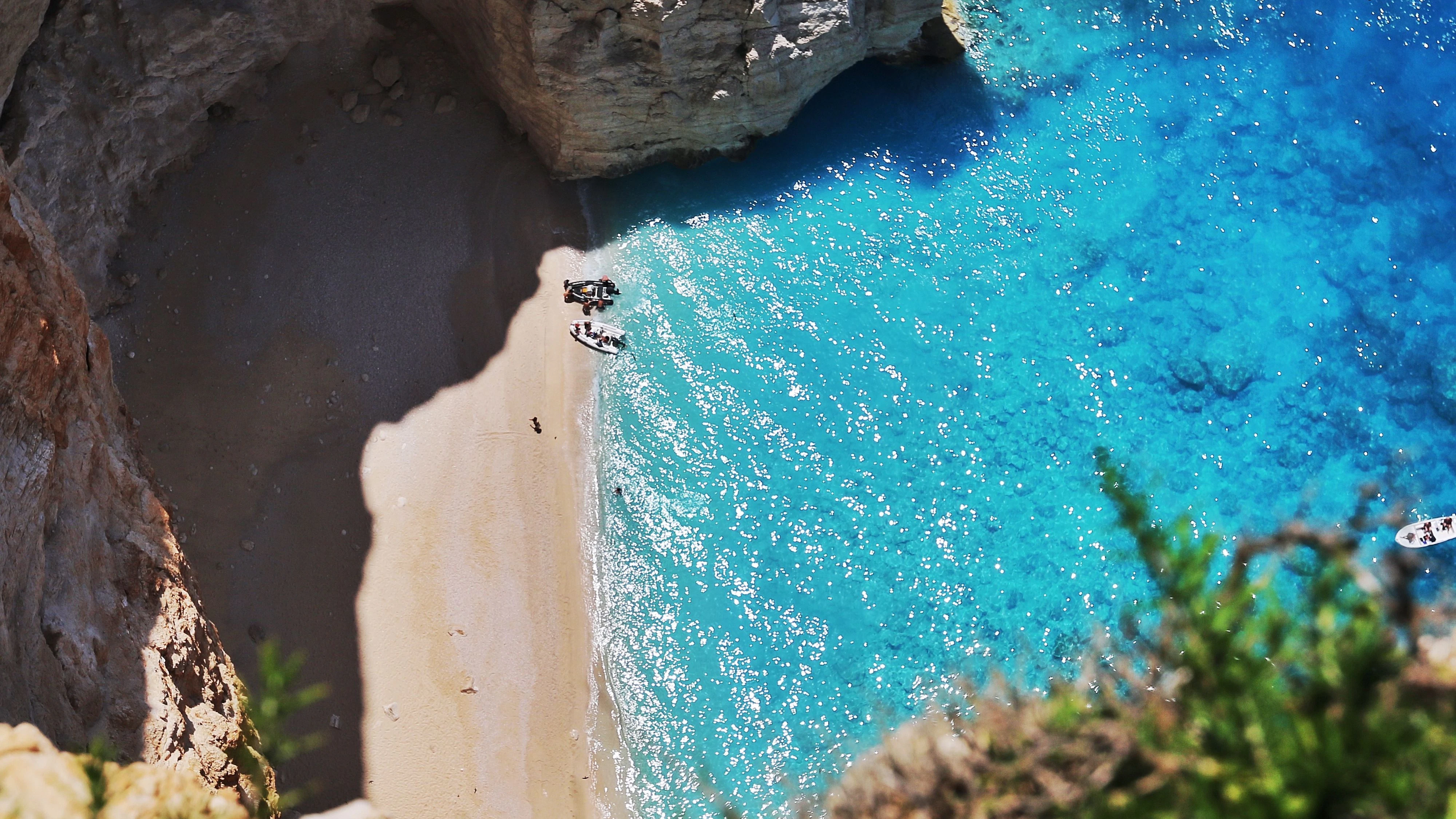 Aerial view of Zakynthos’ iconic Navagio Beach, featuring the famous shipwreck on pristine white sands, surrounded by towering limestone cliffs and crystal-clear turquoise waters. A stunning example of Greece’s natural beauty and Mediterranean charm.