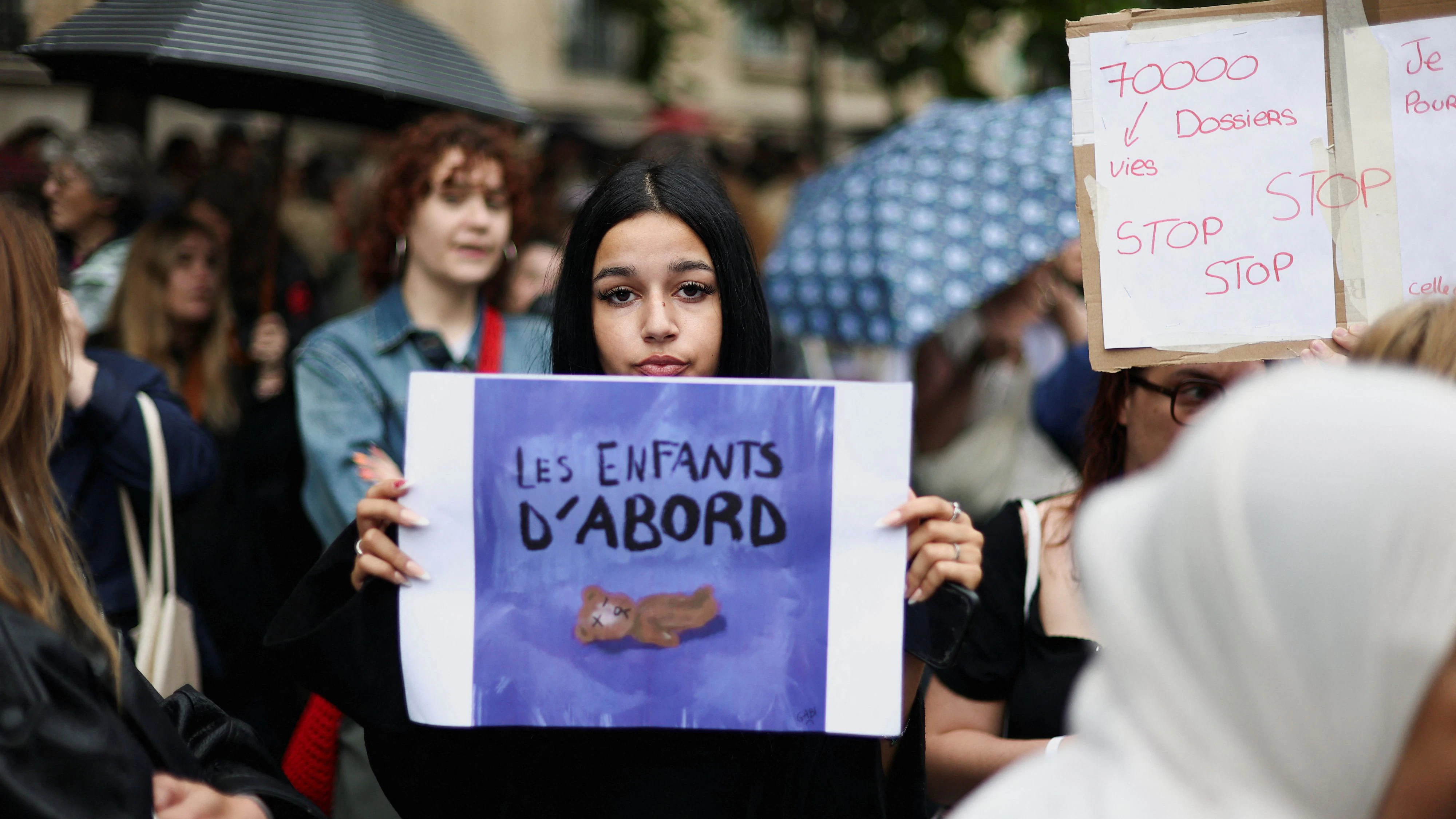 People attend a demonstration, amid nationwide calls to protest the handling by the criminal justice system of previous complaints involving child victims against the main suspect in the killing of 11-year-old Lyhanna, whose body was discovered near Fleurance after a days-long search, near the  Paris courthouse, France, June 8, 2026, in a protest supported by the #NousToutes movement. The sign reads: "Children first". REUTERS/Gonzalo Fuentes