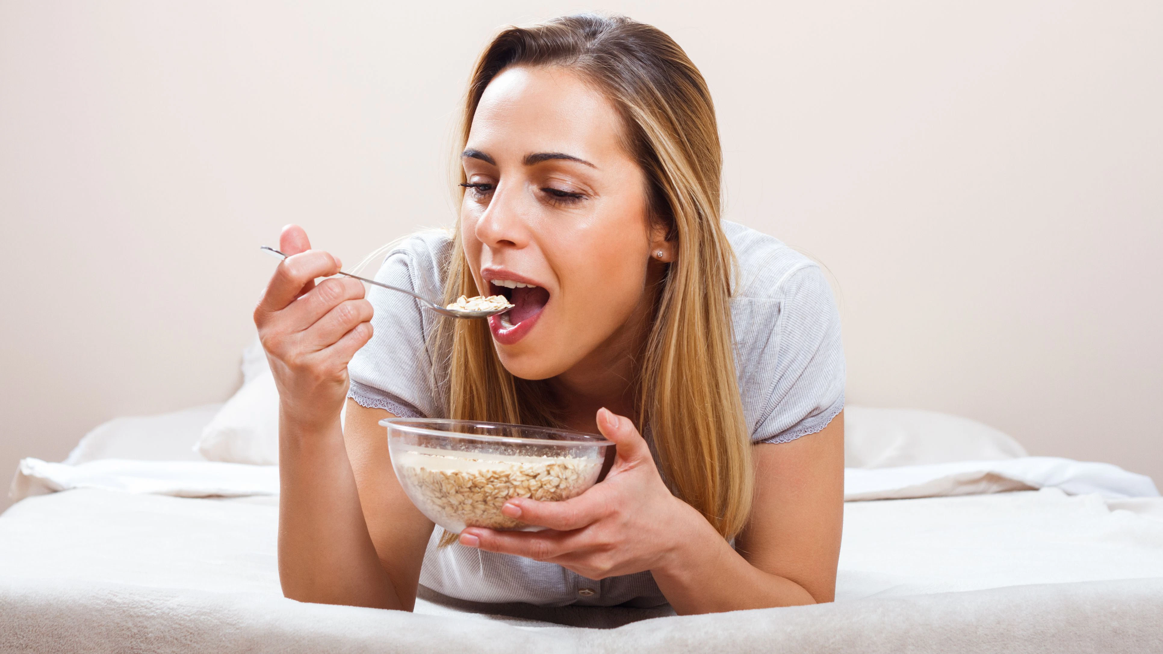 Beautiful woman is having healthy breakfast in bed.