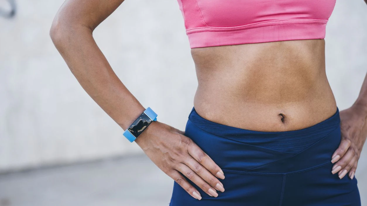 Female athlete with her hands on hips wearing smart watch