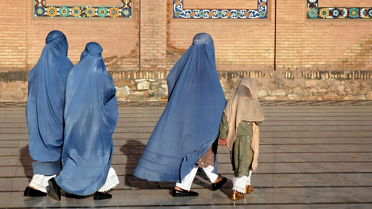 Herat in western Afghanistan. The Great Mosque of Herat (Friday Mosque or Jama Masjid). Three women in burqas and a girl walk at the front of the mosque. The mosque is one of the oldest in Afghanistan. (Unrecognizable people)