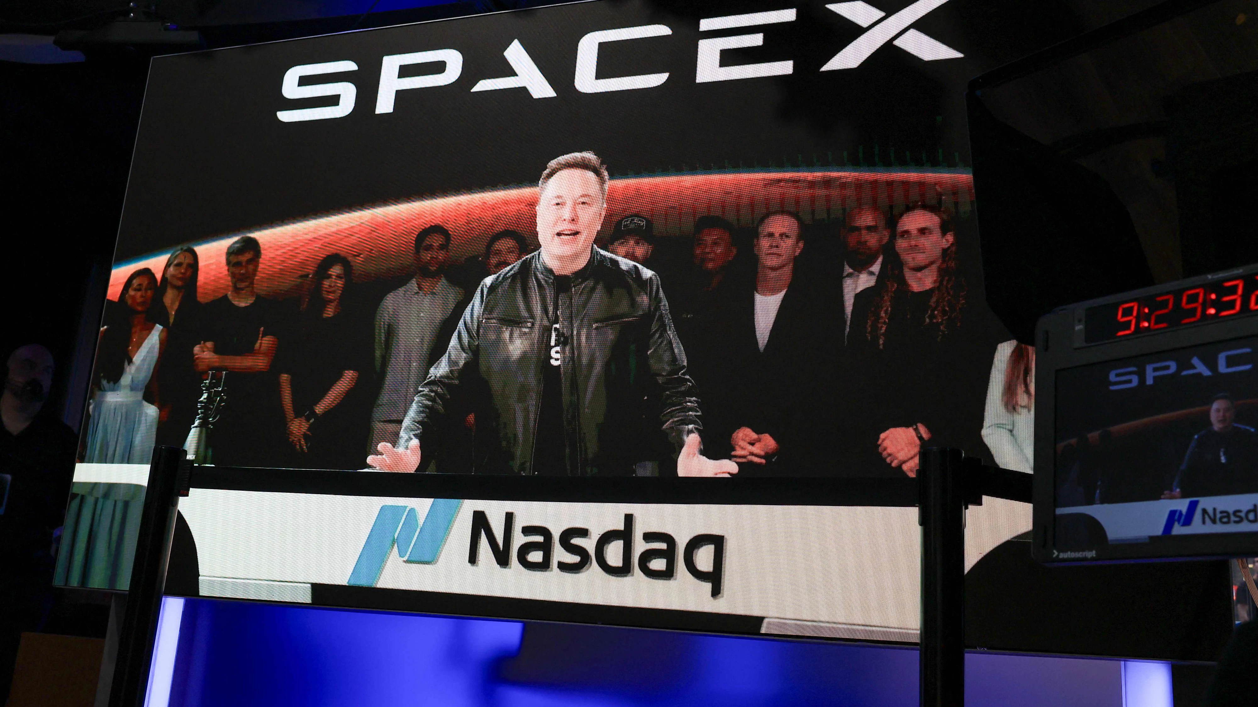 SpaceX CEO Elon Musk, displayed on a screen remotely from SpaceX headquarters in Starbase, Texas, speaks before the launch of SpaceX's initial public offering (IPO) at the Nasdaq MarketSite in New York on June 12, 2026. Elon Musk's SpaceX begins trading on the Nasdaq exchange on Friday with the biggest initial public offering in history expected to make the polarizing entrepreneur the world's first trillionaire. The company priced more than 555 million shares at $135 each in a filing with the US markets regulator on Thursday, placing SpaceX in the top 10 of Wall Street's biggest companies with a valuation of just under $1.8 trillion -- ahead of Tesla, Facebook-owner Meta and Walmart. (Photo by TIMOTHY A. CLARY / AFP)