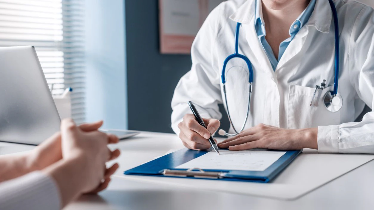 Doctor sitting at desk and writing a prescription for her patient