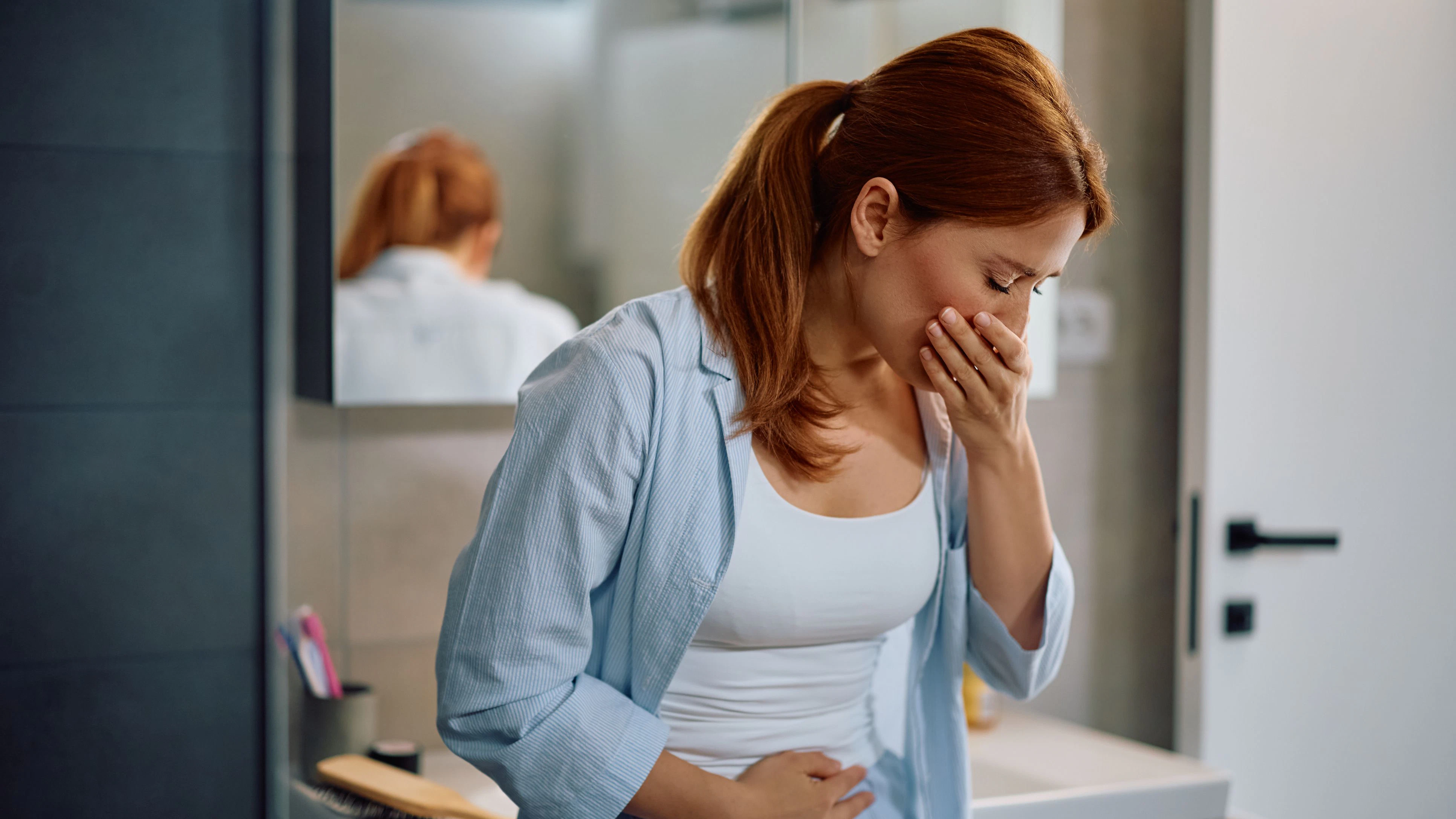 Mid adult woman with morning sickness in the bathroom.