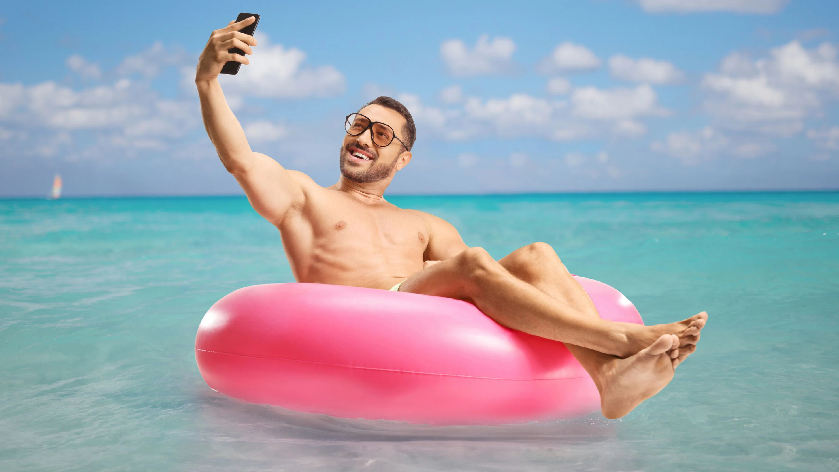 Man sitting on a swimming ring and taking a selfie with a smartphone in the sea