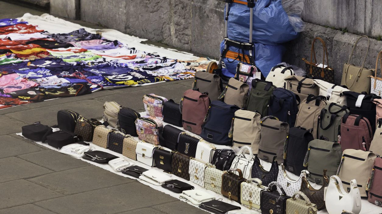 A street with copies of designer bags and soccer team shirts for sale.