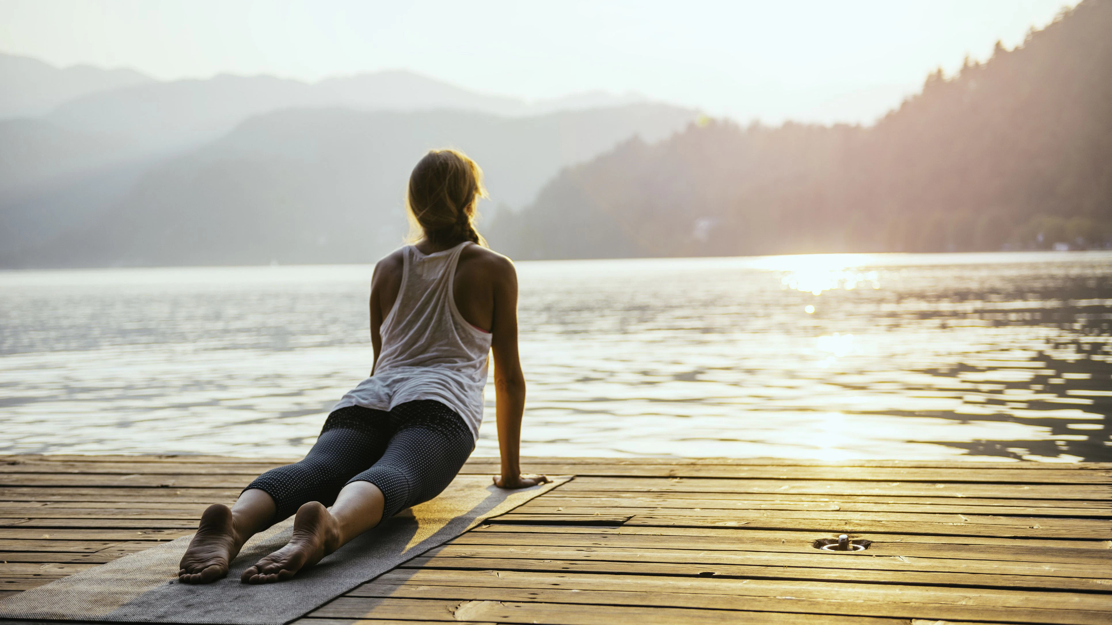 Beautiful woman practicing Yoga by the lake - Sun salutation series - Upward facing dog - Toned image