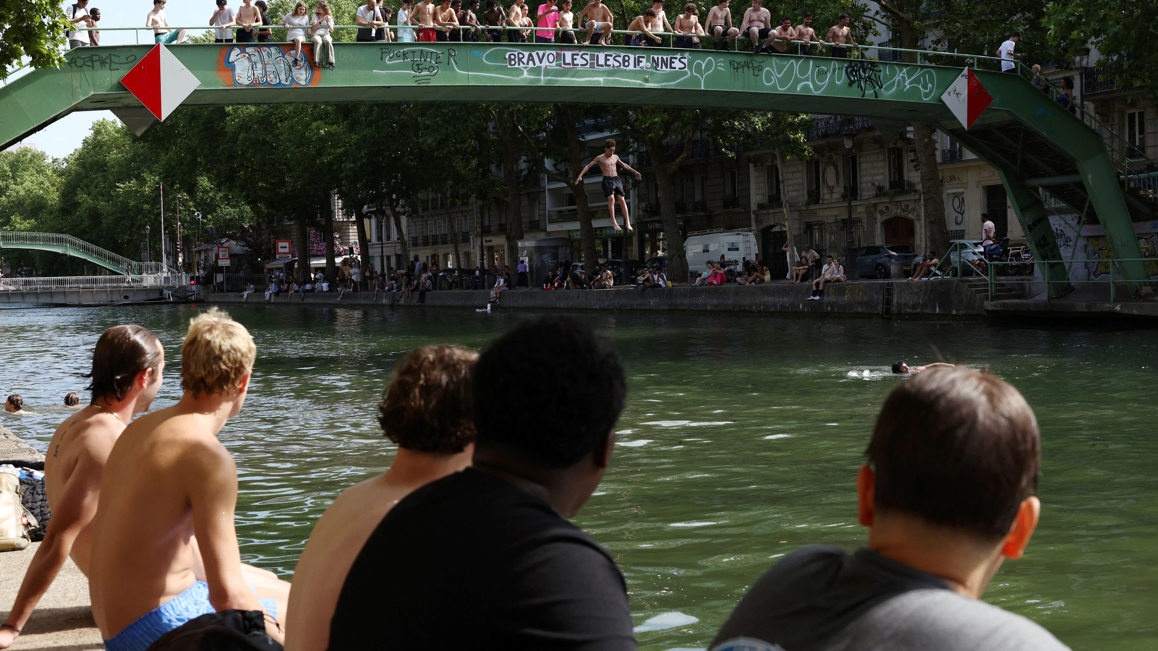 Young people jump from a bridge into the Canal Saint-Martin on a sunny and warm summer day in Paris as an early summer heatwave hits France, July 2, 2025. REUTERS/Tom Nicholson