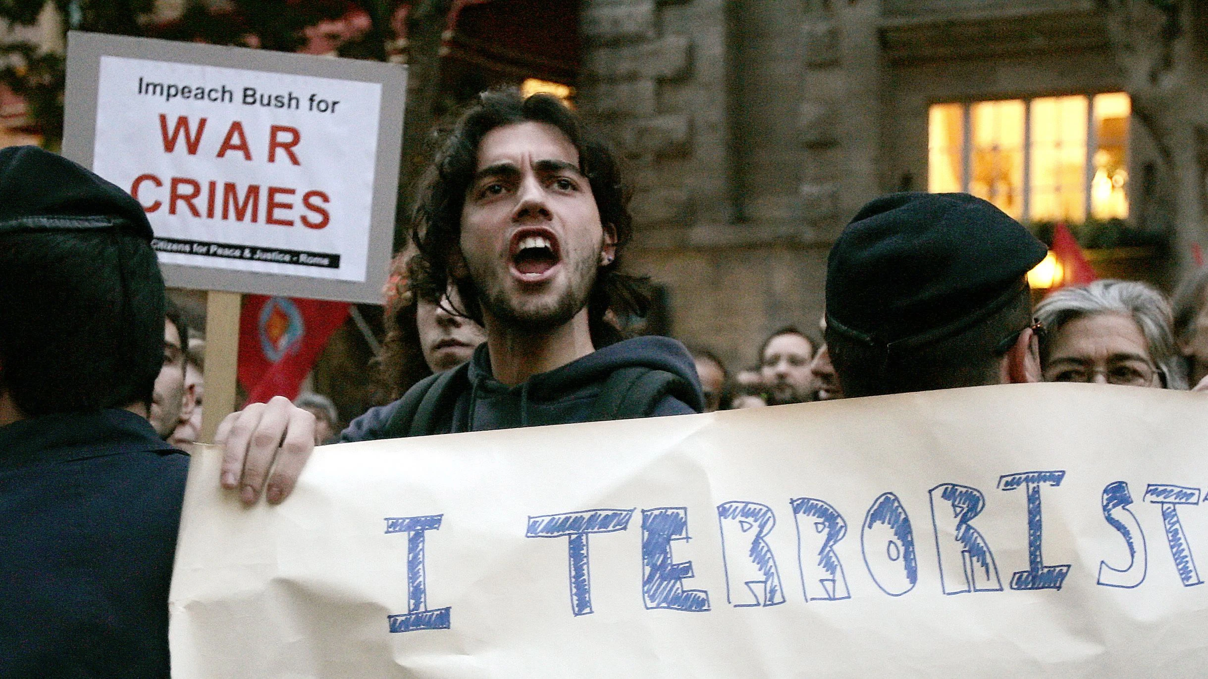 A demonstrator holds a banner reading "Terrorist" as he protests outside the U.S. embassy in downtown Rome November 14, 2005, during a protest against the reported use of banned weapons against Iraqi civilians. The U.S. military in Iraq denied a report shown on Italian state television last week saying U.S. forces used incendiary white phosphorus against civilians in a November 2004 offensive on the Iraqi town of Falluja. REUTERS/Alessandro Bianchi
