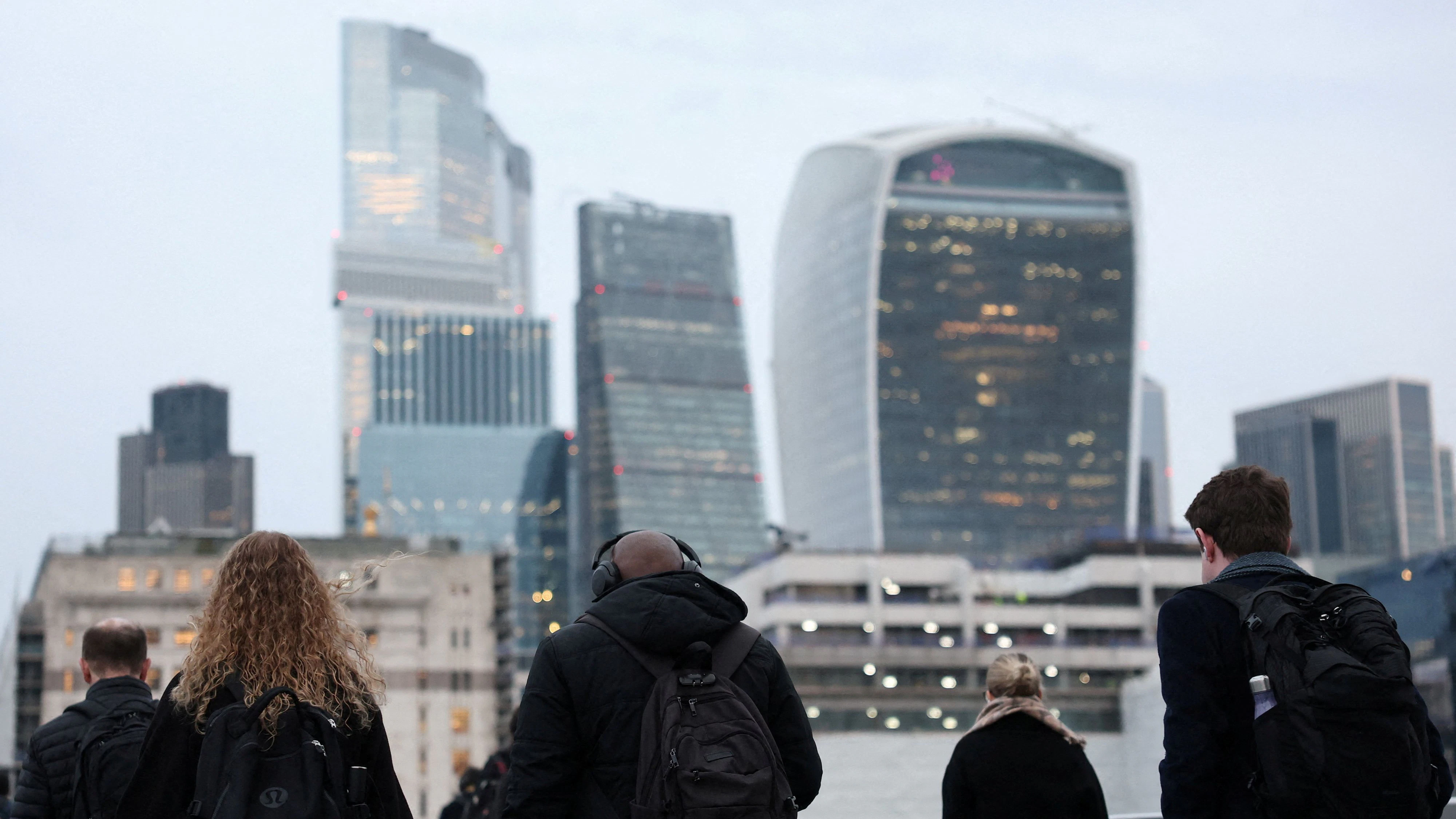 FILE PHOTO: Workers cross London Bridge during the morning rush-hour with skyscrapers of the City of London financial district seen behind, in London, Britain, December 16, 2025. REUTERS/Toby Melville/File Photo