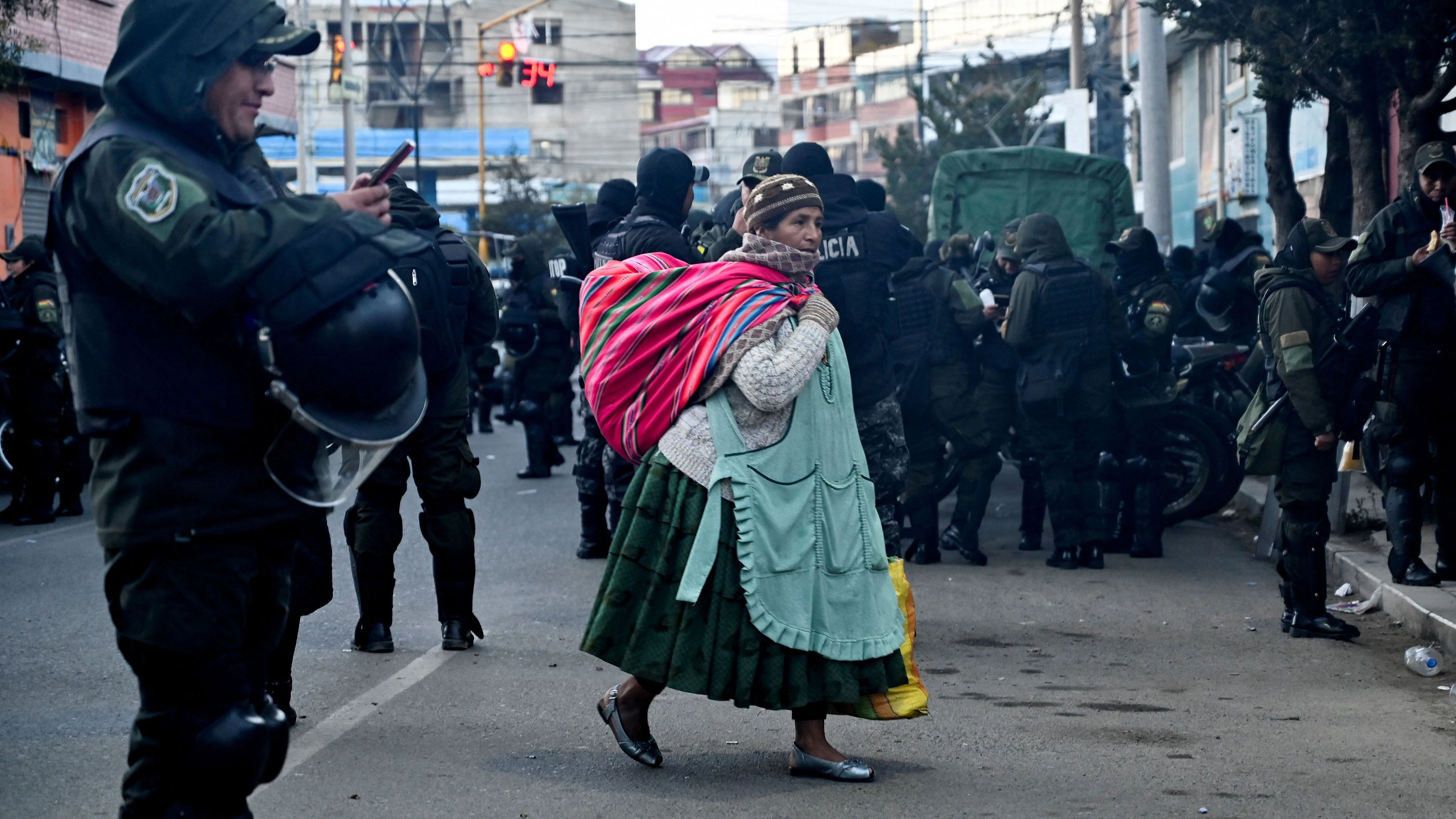 A woman walks by as police officers prepare to go out and unblock the La Paz-Oruro highway in the city of El Alto, after Bolivian President Rodrigo Paz declared a nationwide state of emergency following weeks of violence and blockades, in Bolivia, June 20, 2026. REUTERS/Claudia Morales 
