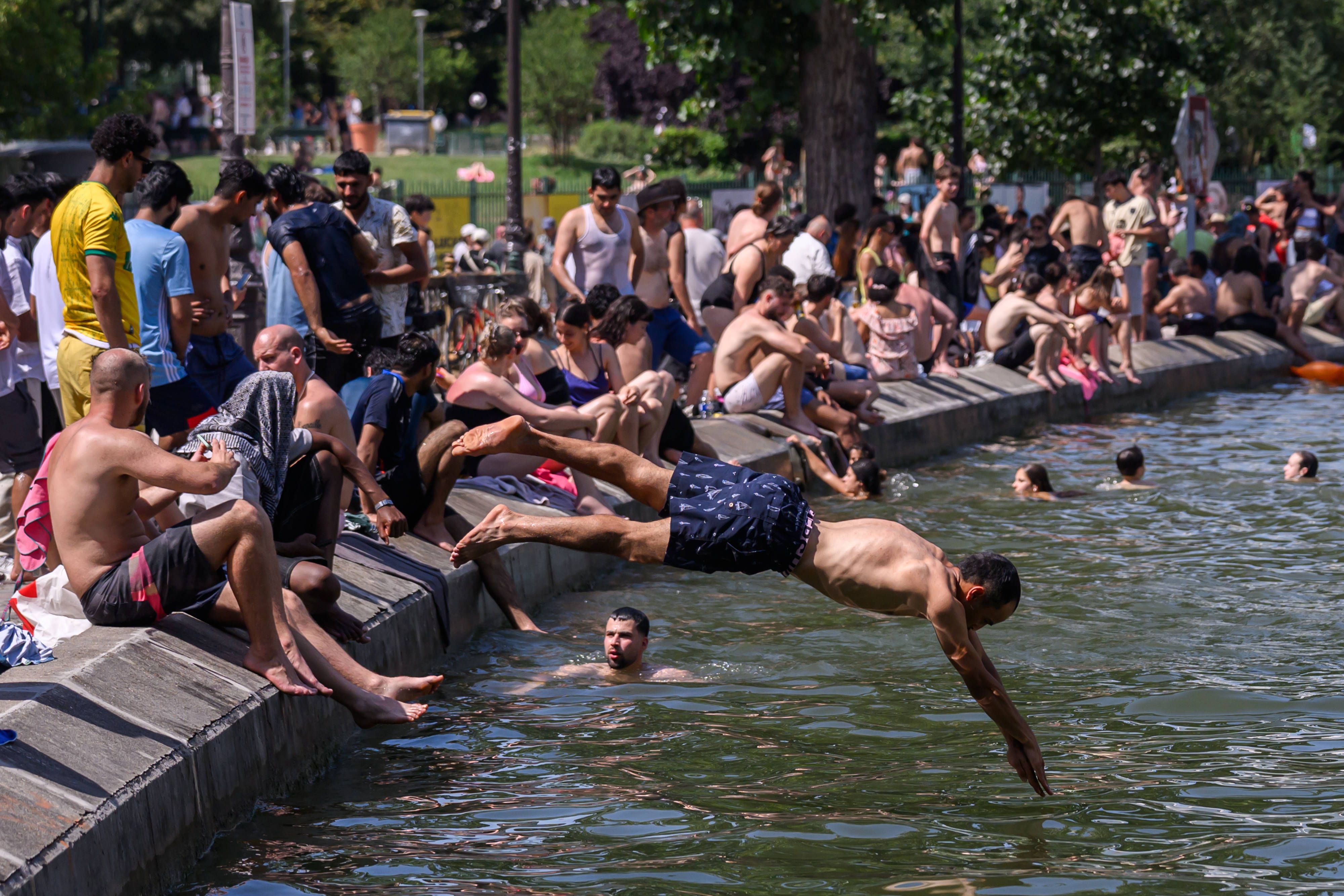 Hunderte junger Menschen springen von Brücken und suchen Abkühlung an den Ufern des Canal Saint-Martin, während am 21. Juni 2026 eine Hitzewelle Paris heimsucht.