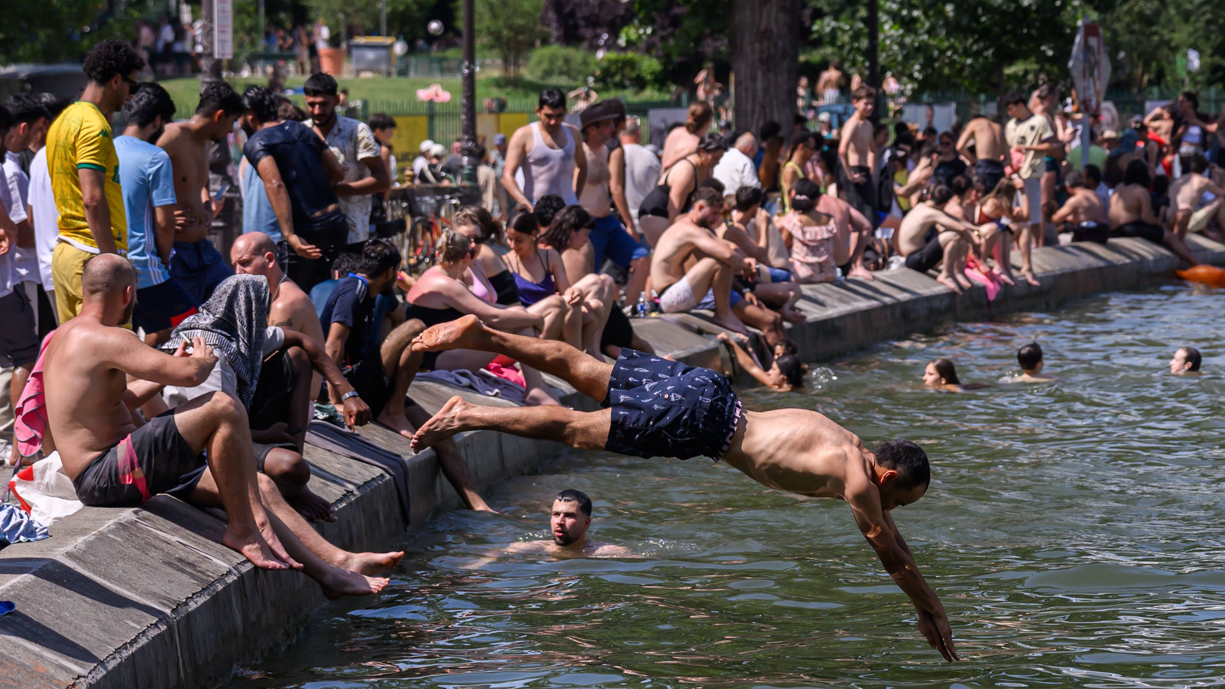 Hunderte junger Menschen springen von Brücken und suchen Abkühlung an den Ufern des Canal Saint-Martin, während am 21. Juni 2026 eine Hitzewelle Paris heimsucht.