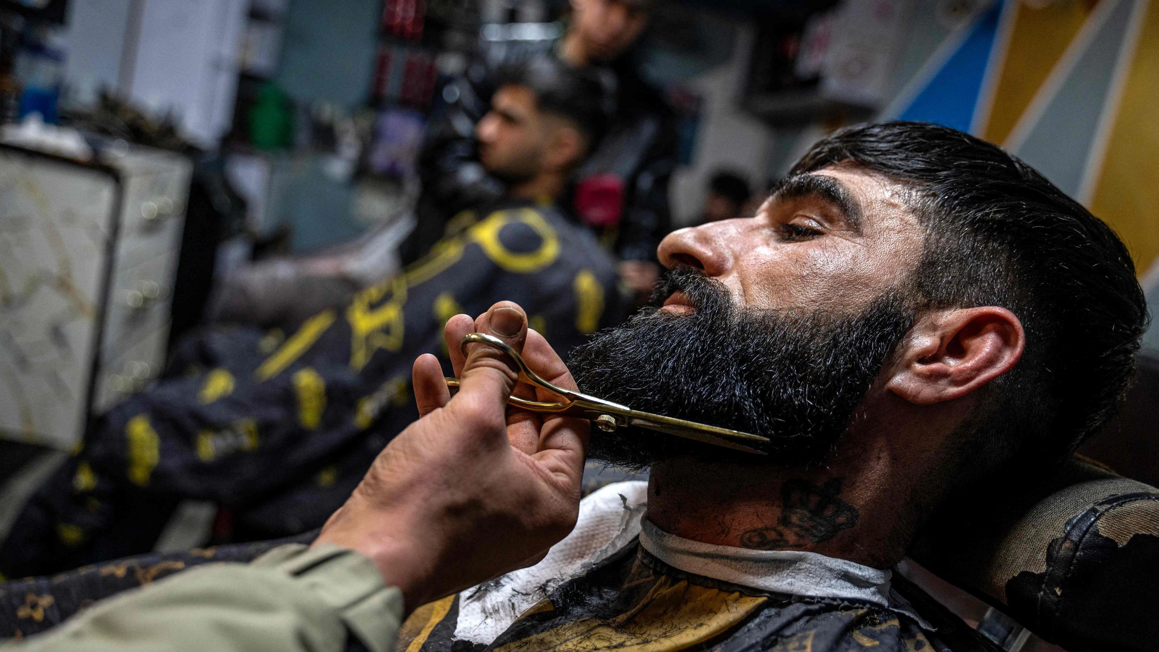This photograph taken on February 11, 2026 shows an Afghan barber trimming a customer's beard at a salon in Kabul. Barbers in Afghanistan risk detention for trimming men's beards too short, they told AFP, as the Taliban authorities enforce their strict interpretation of Islamic law with increasing zeal. (Photo by Wakil KOHSAR / AFP) / To go with 'Afghanistan-Police-Rights-Beard', FOCUS