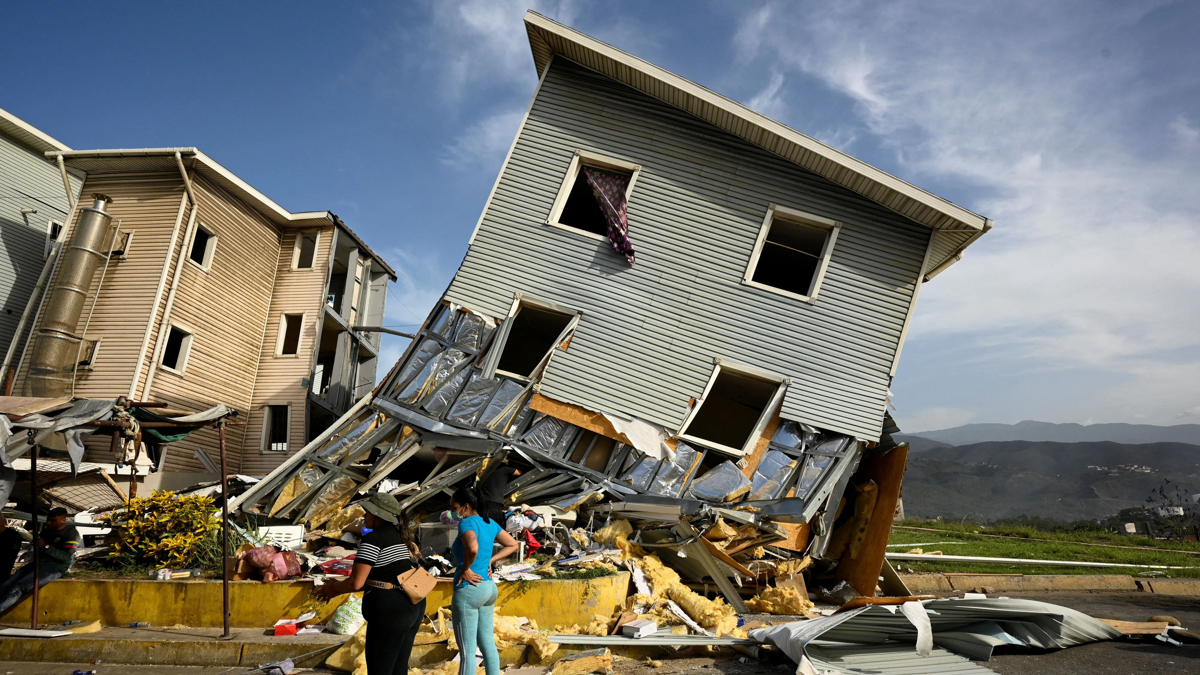 Women stand near the remains of a building damaged in the aftermath of earthquakes in La Guaira, Venezuela, June 25, 2026. REUTERS/Maxwell Briceno 