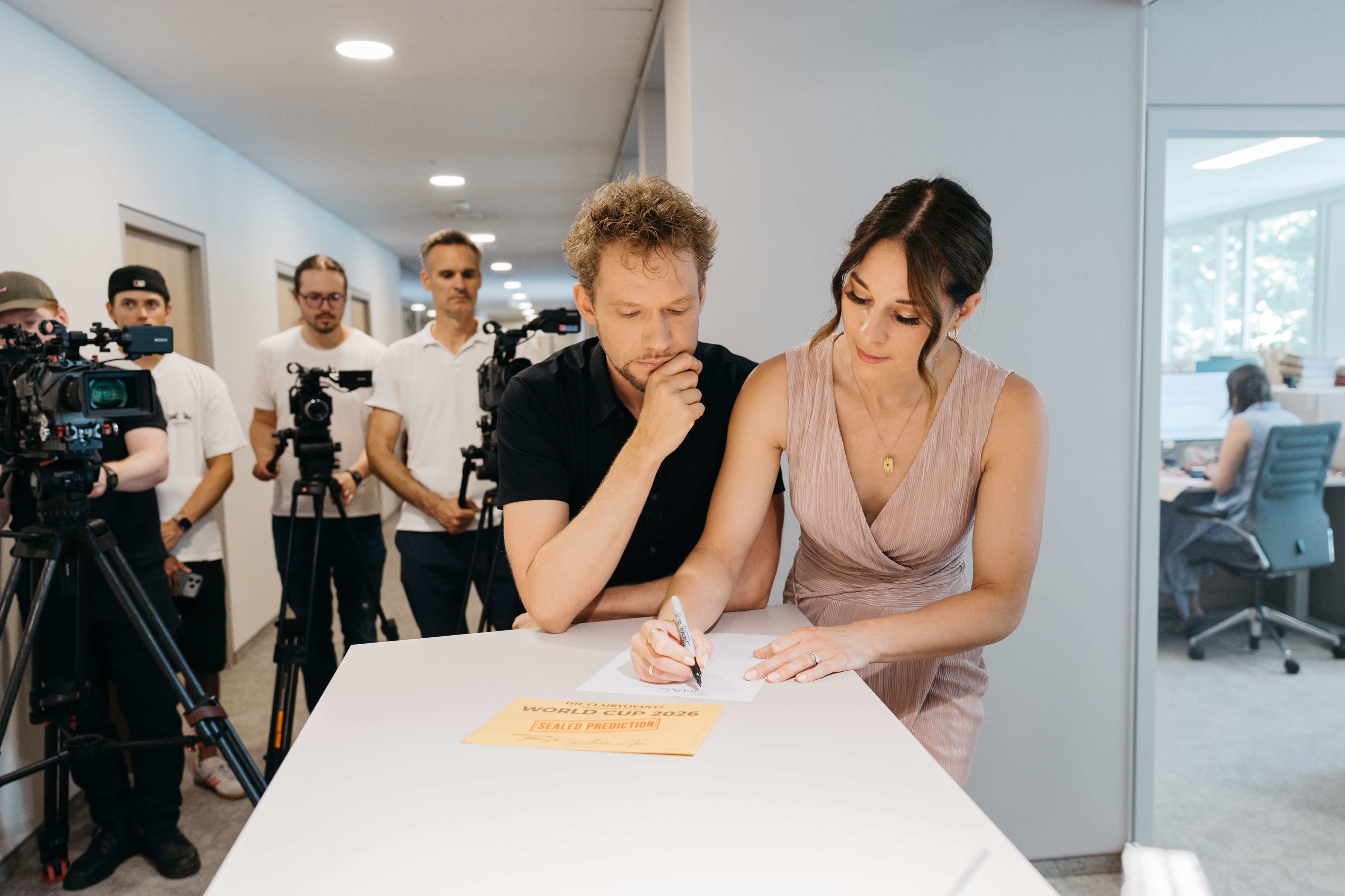 Thommy Ten und Amélie van Tass schreiben ihren WM-Tipp auf ein Blatt Papier