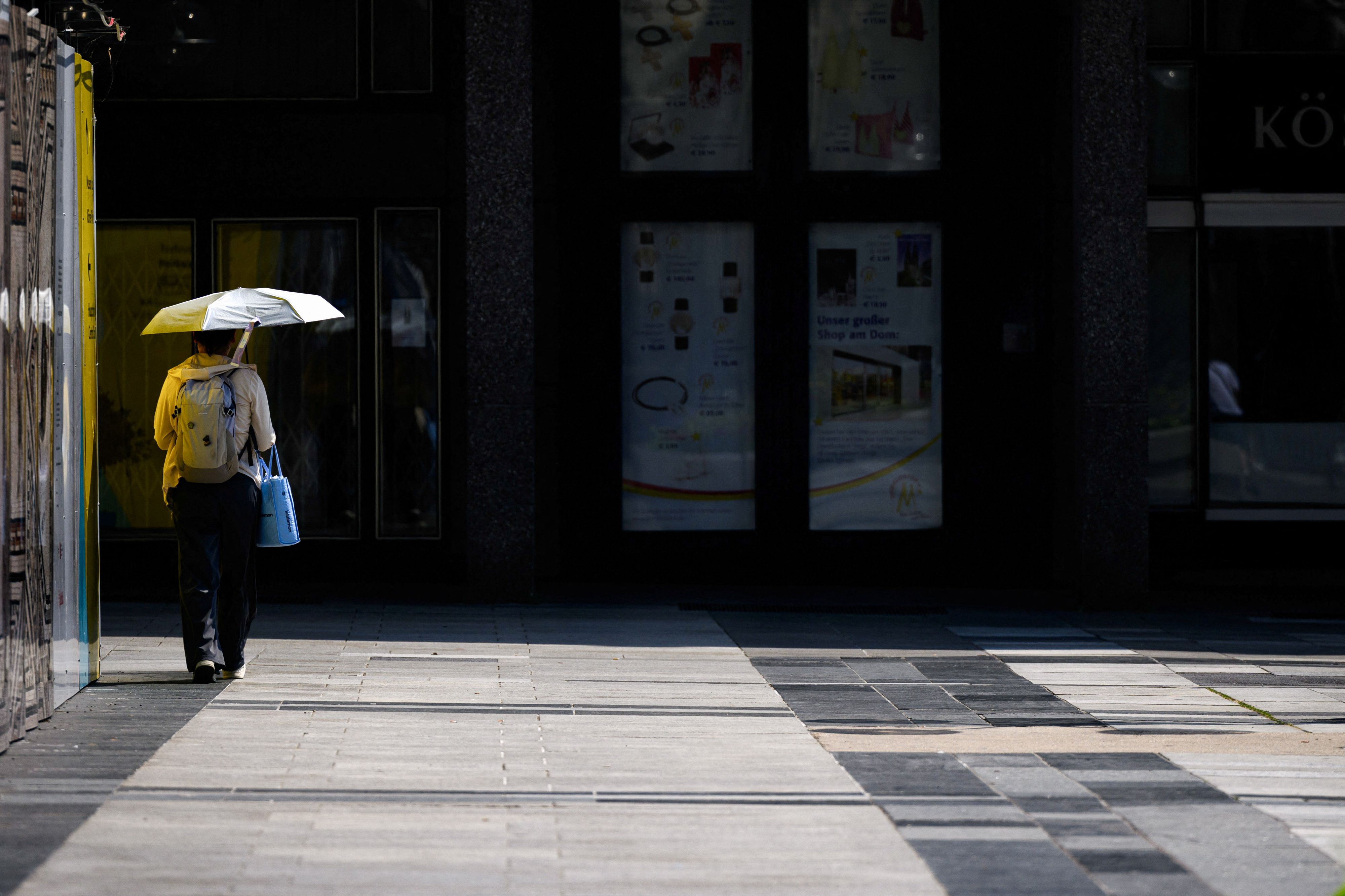 Hitze in Köln - hier schützt sich eine Person mit einem Regenschirm,