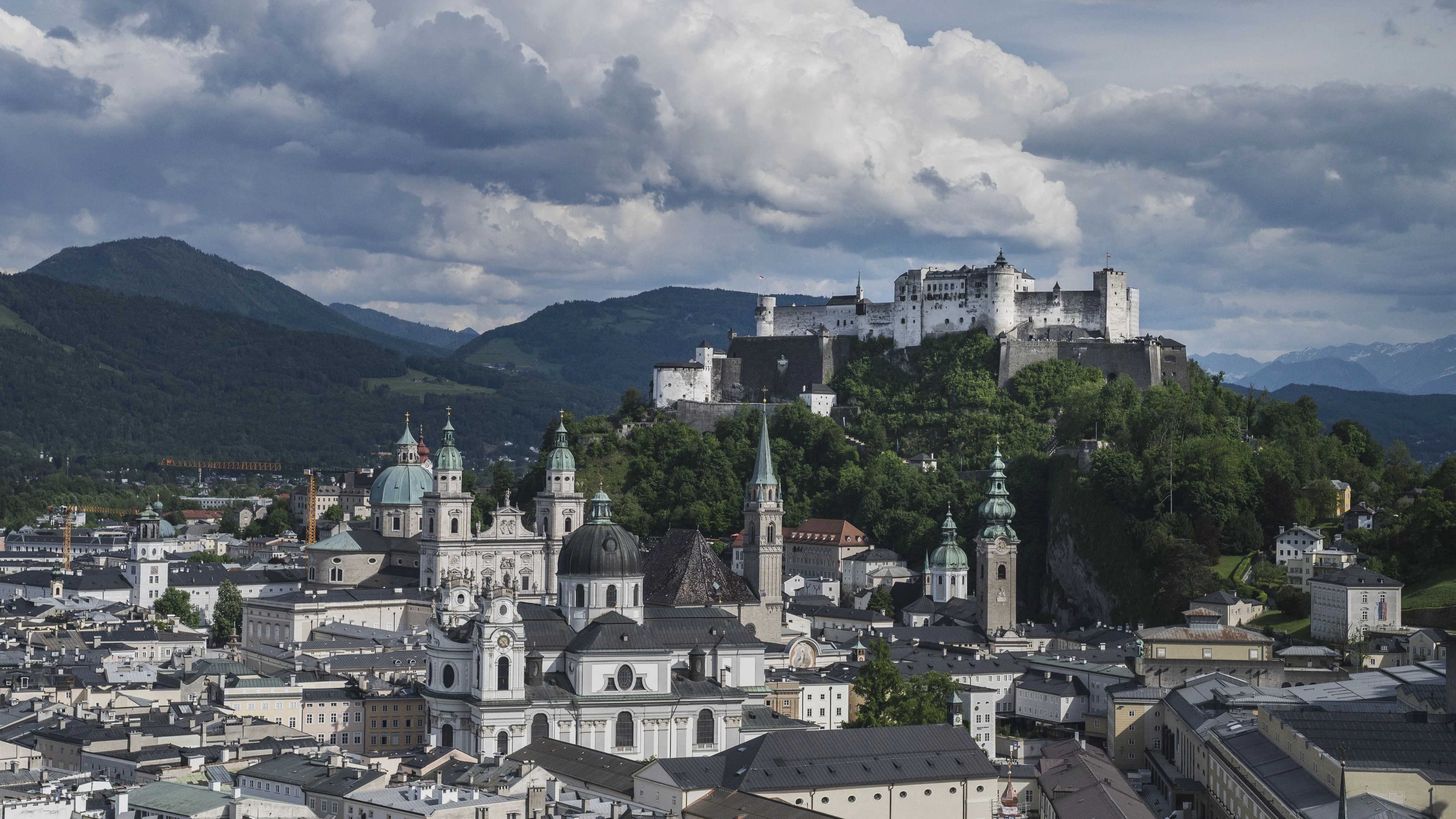 View of the Mozart city of Salzburg with the Hohensalzburg Fortress on the Mönchsberg with rain clouds on the horizon.