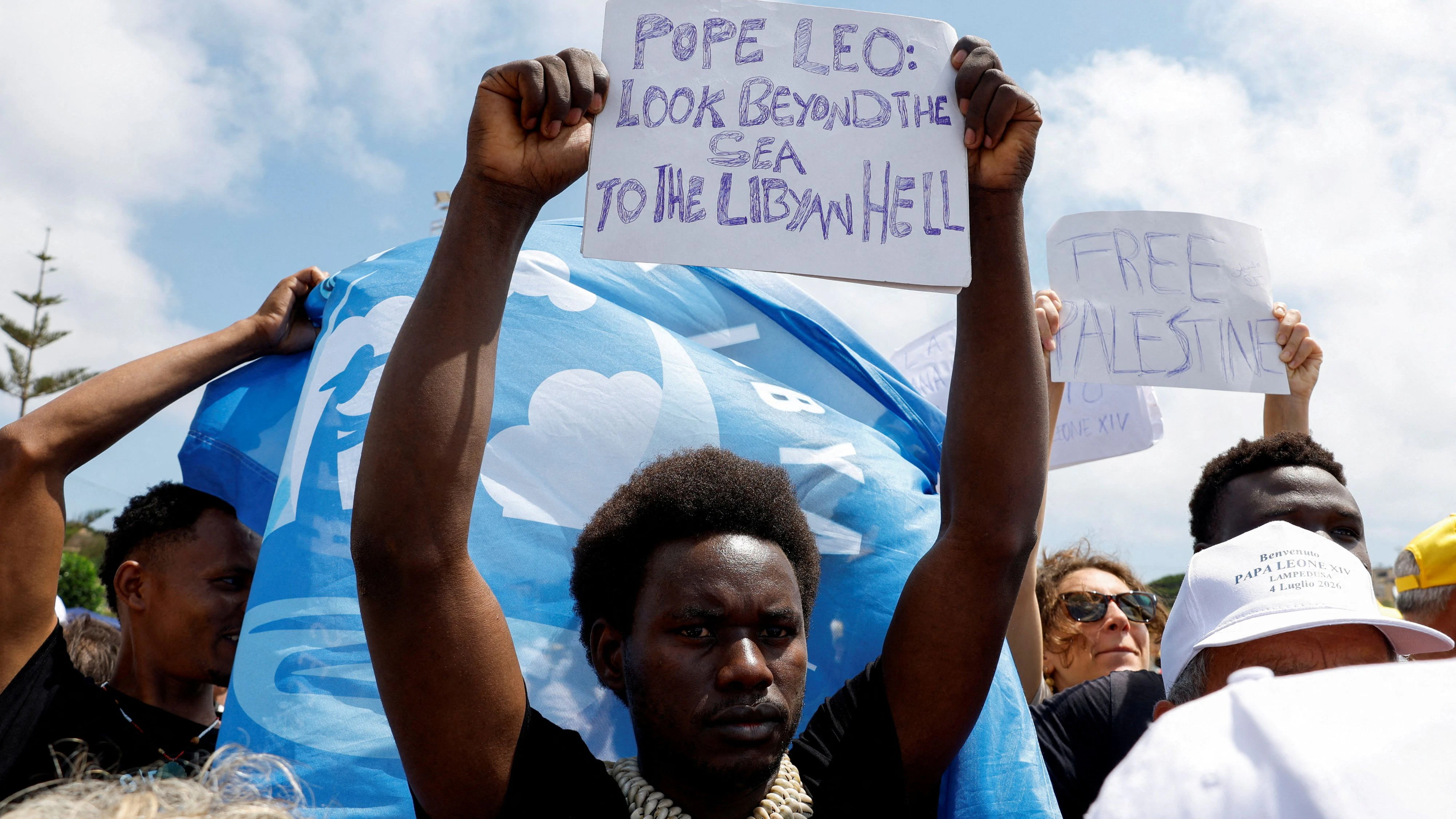 Auf Lampedusa gestrandete Migranten unter den Besuchern rufen den Papst dazu auf, auf die "libysche Hölle" auf der anderen Seite des Ozens zu blicken.