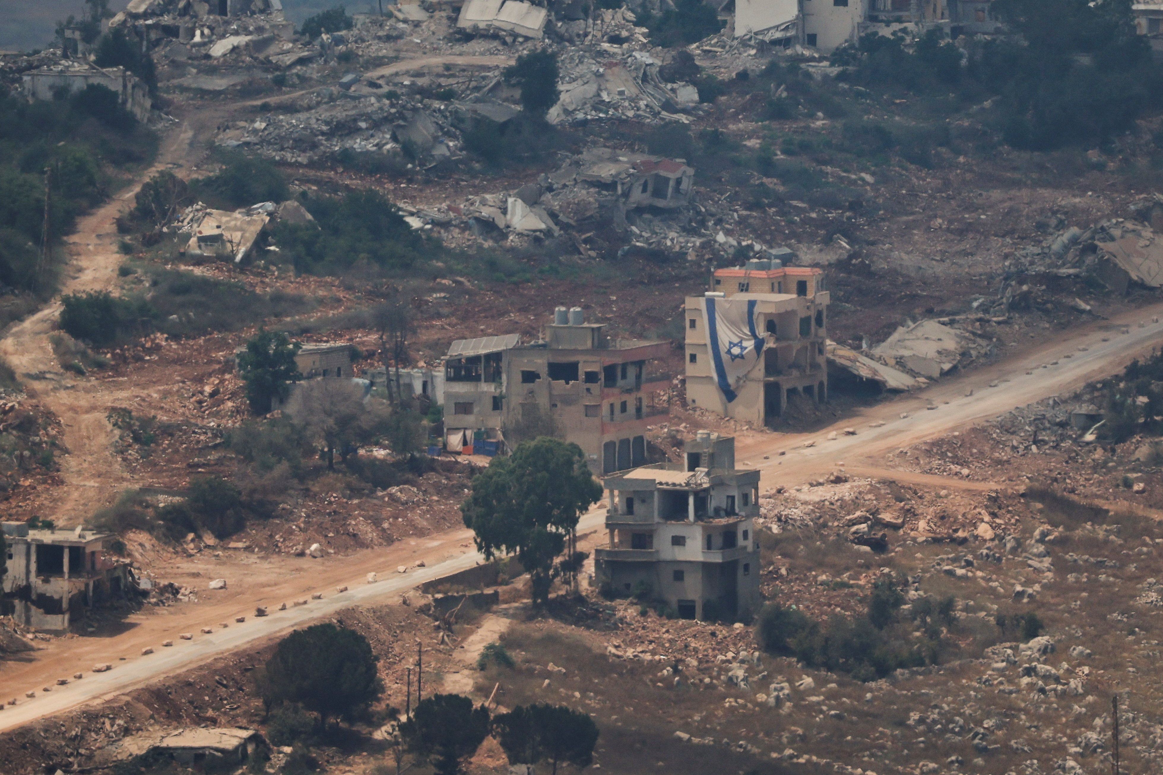 Eine israelische Flagge hängt an einem Gebäude im Libanon, gesehen von der israelischen Seite der Grenze zwischen Israel und dem Libanon im Norden Israels.