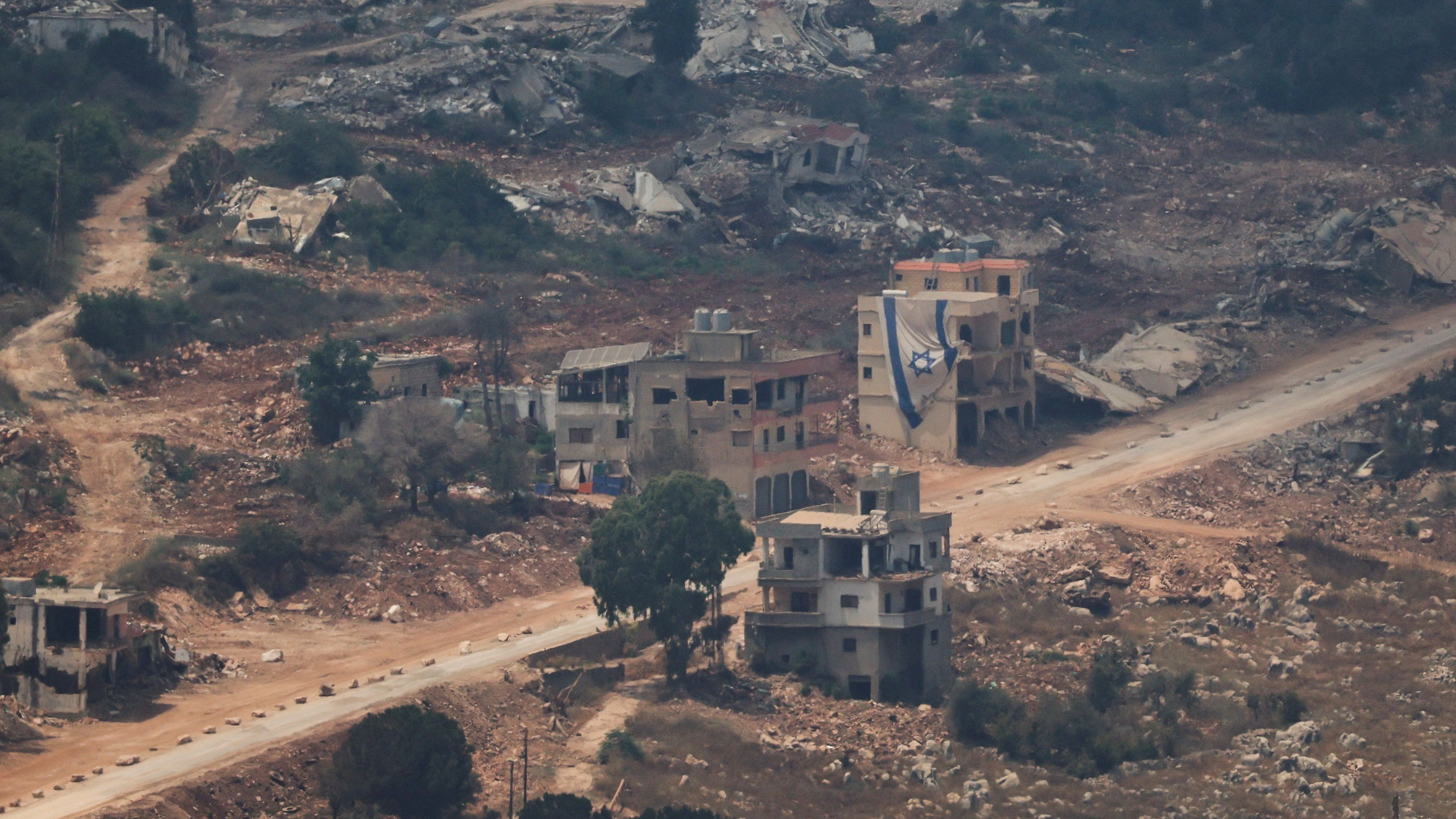 Eine israelische Flagge hängt an einem Gebäude im Libanon, gesehen von der israelischen Seite der Grenze zwischen Israel und dem Libanon im Norden Israels.