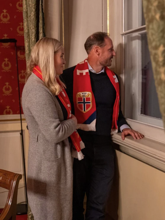 Mette-Marit und Haakon blicken aus dem Fenster.
