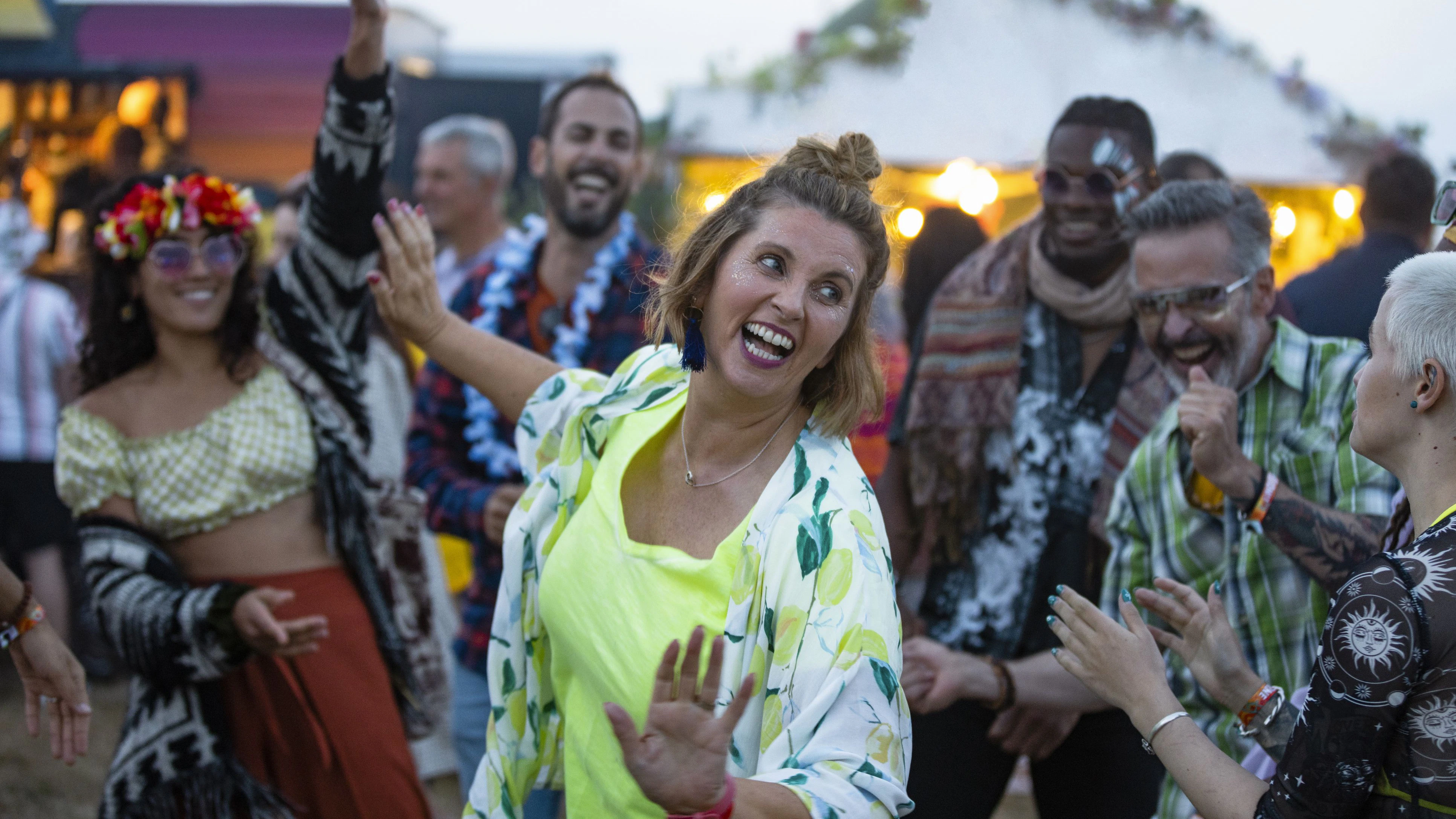 A small group of friends at a festival all dancing together and having a good time. Everyone is happy and smiling and sharing positive energy.