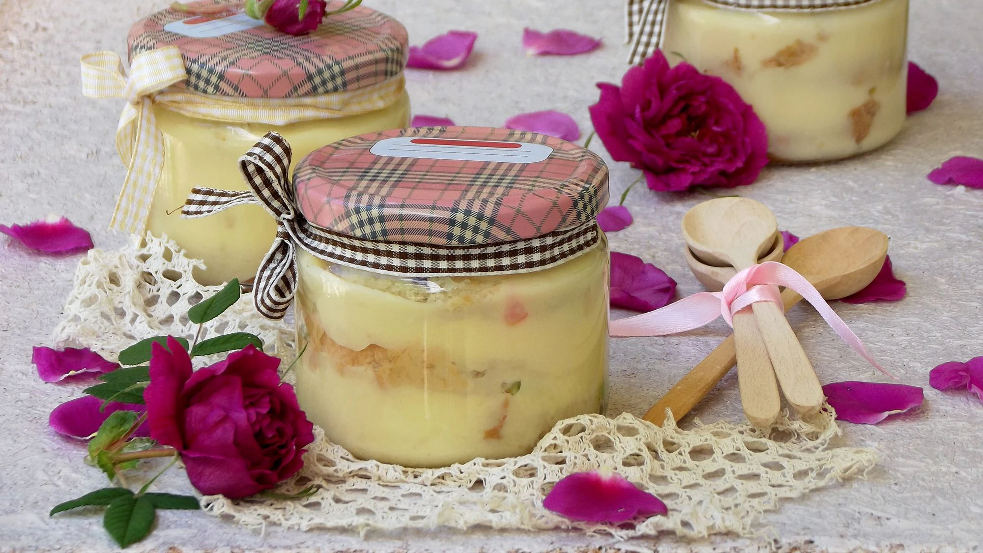 Dessert with rose petals in a jar on a wooden background