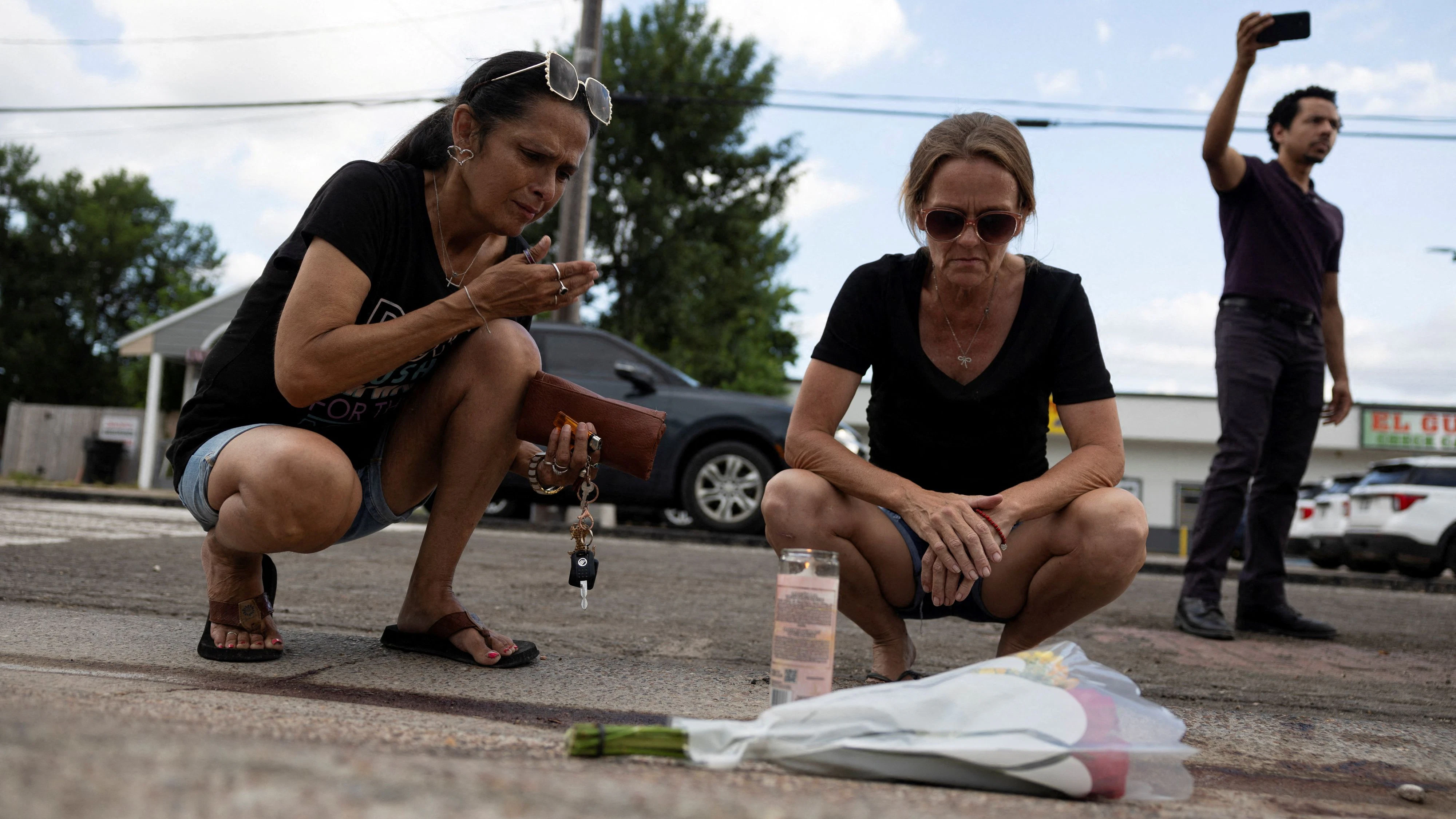 Gina Danielsen and Rhonda Smith place a candle next to flowers, next to the scene where an ICE agent fatally shot a Mexican motorist, identified as Lorenzo Salgado Araujo, during a vehicle stop in Houston, Texas, U.S., July 7, 2026.   REUTERS/Antranik Tavitian REFILE - UPDATING SPELLING  