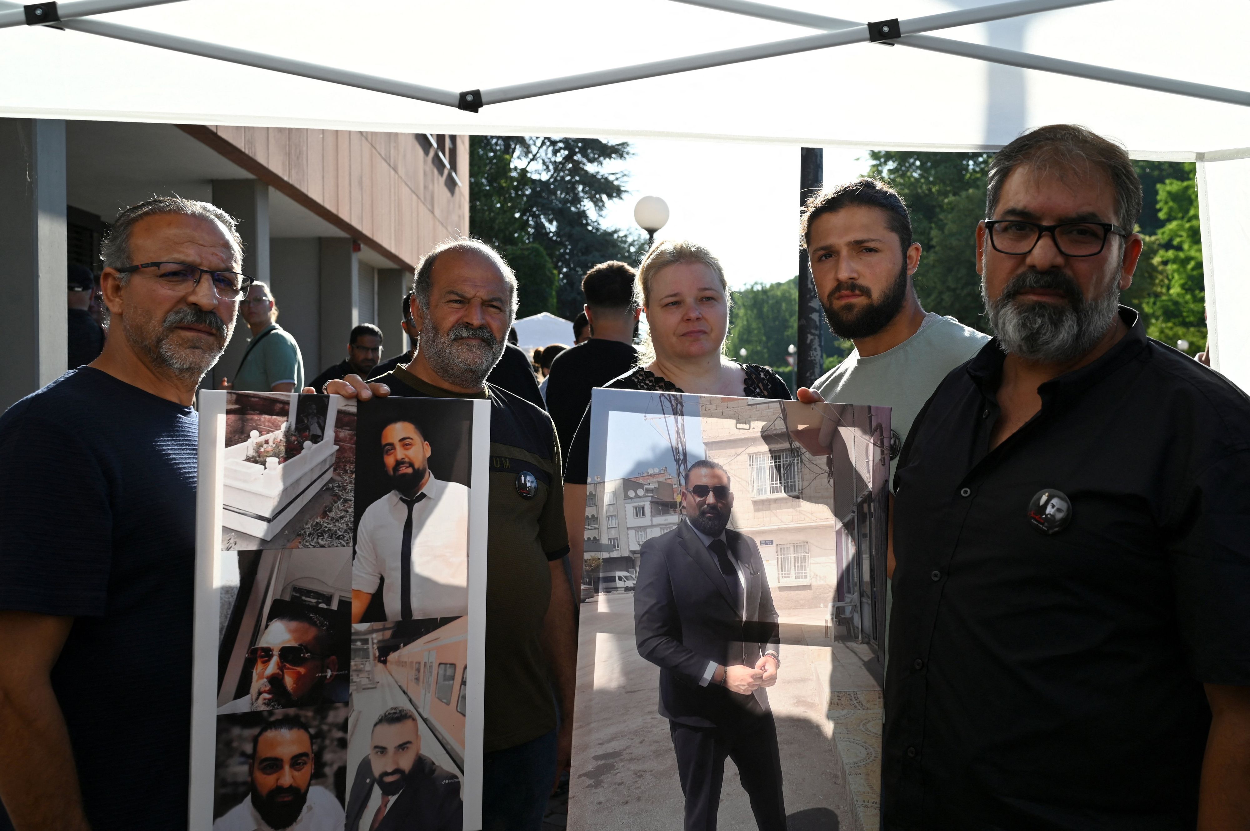 Erdal C., der Vater des getöteten Zugbegleiters Serkan C., und weitere Familienangehörige halten Fotos des Verstorbenen in den Händen. 