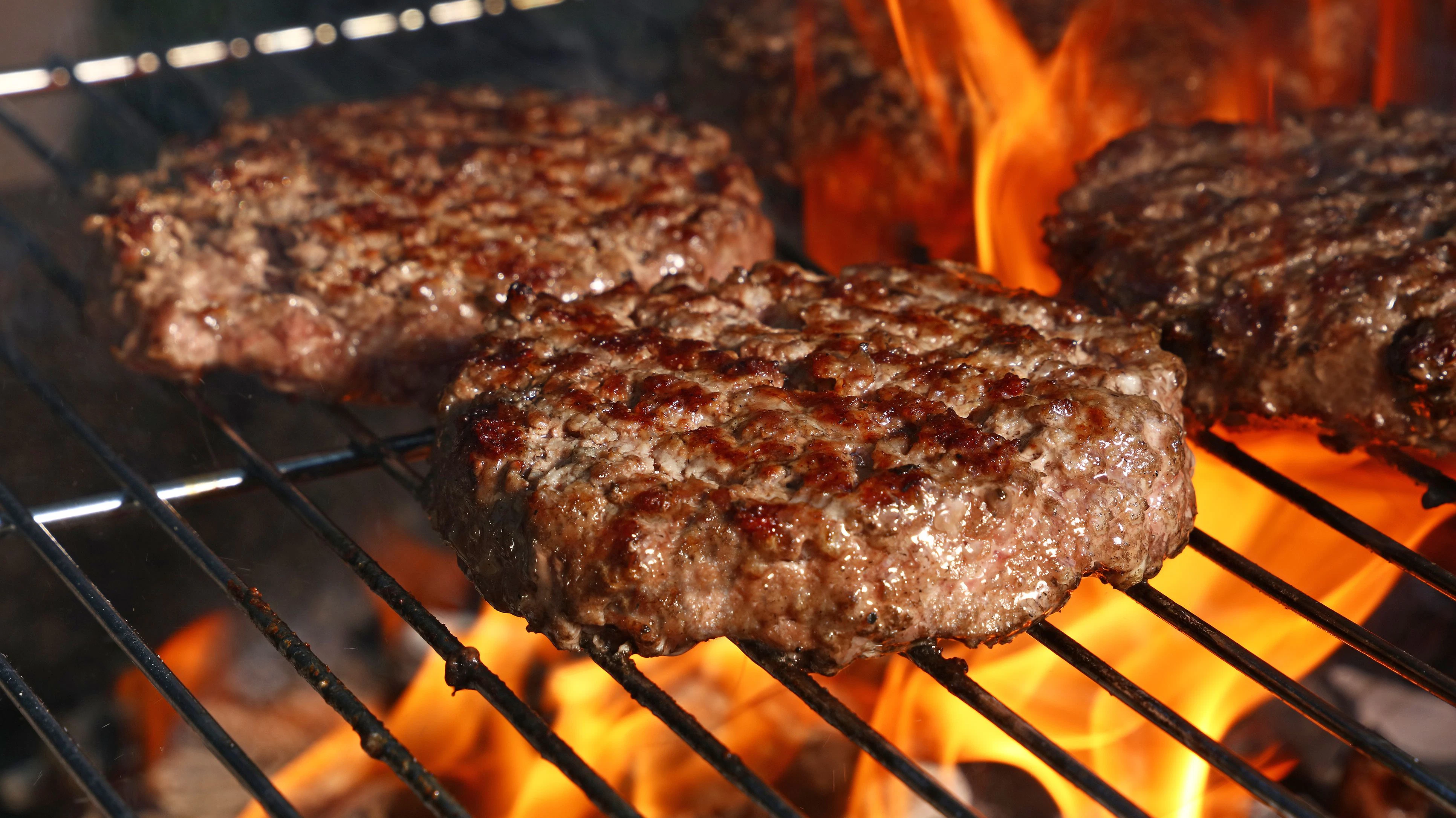 Close up beef or pork meat barbecue burgers for hamburger prepared grilled on bbq fire flame grill, high angle view
