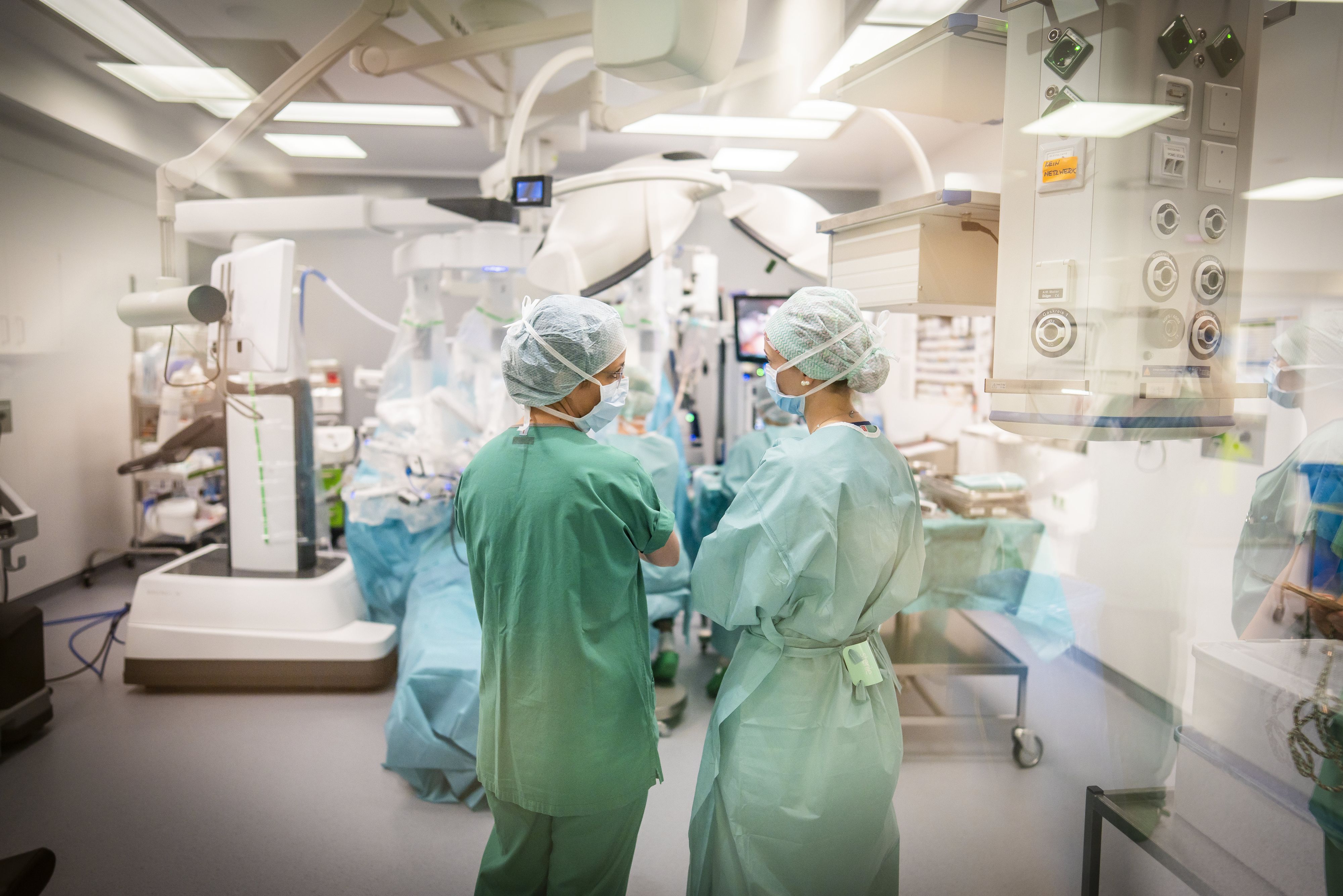 Ein OP-Team steht während einer Bauchoperation vor dem Operationsroboter „DAVINCI“ im zentralen Operationssaal und bespricht den Eingriff.