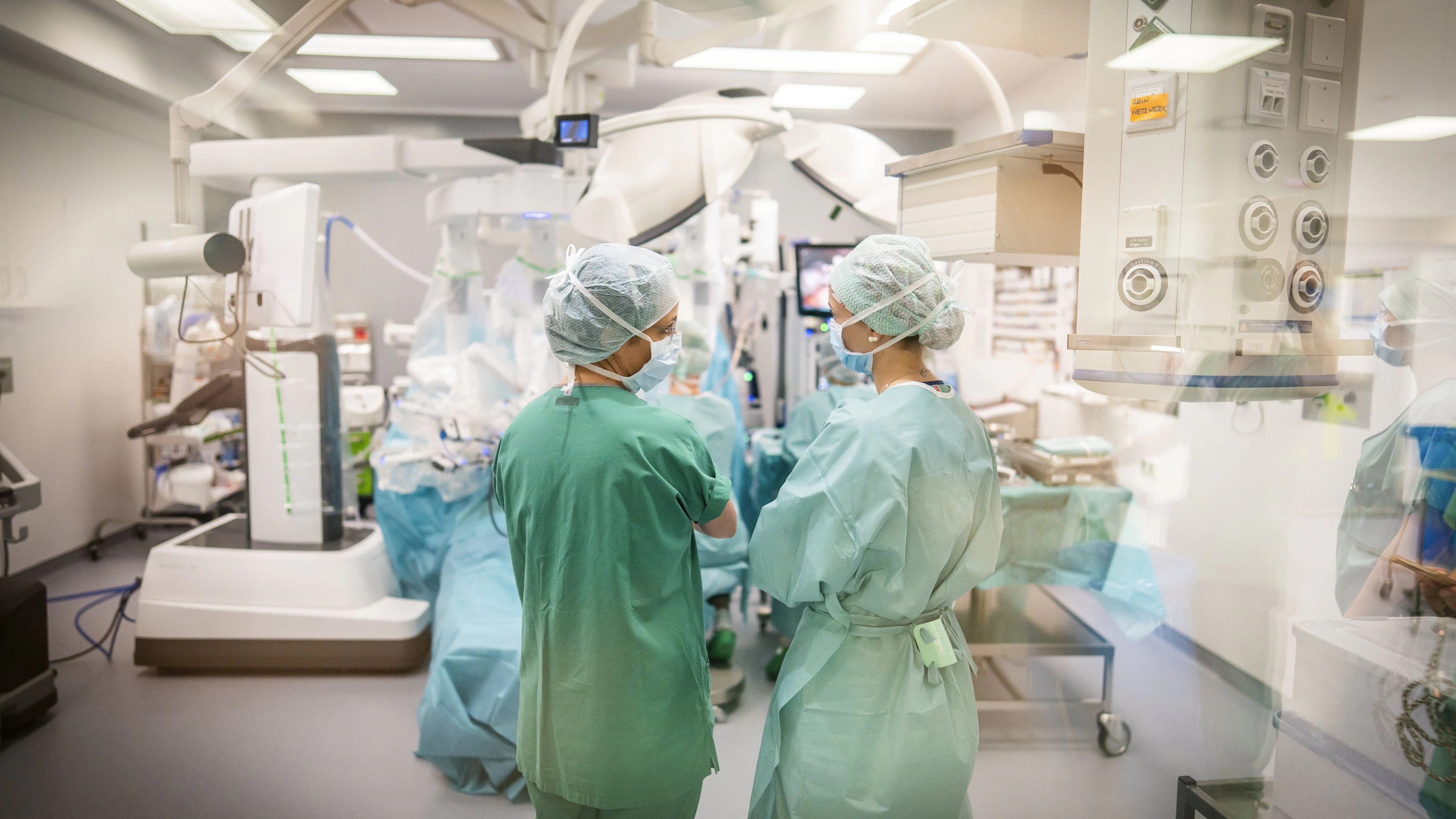 Ein OP-Team steht während einer Bauchoperation vor dem Operationsroboter „DAVINCI“ im zentralen Operationssaal und bespricht den Eingriff.