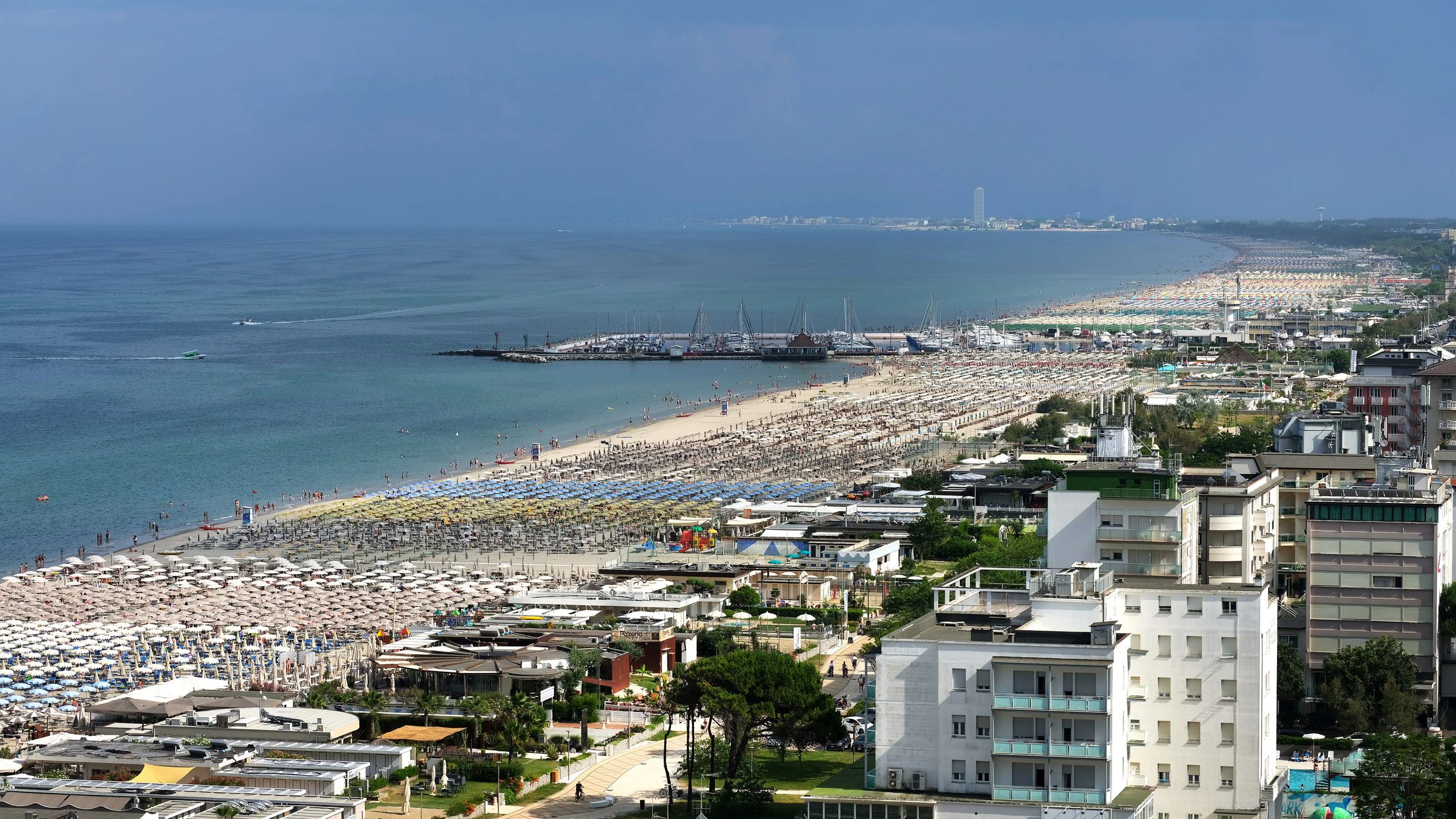 Cervia-Milano Marittima, Ravenna province, Italy June 23, 2023. Panoramic views of the sea and beach of Cervia a few kilometers from the city of Ravenna, Italy. The Riviera Romagnola is a stretch of coastline, overlooking the Upper Adriatic Sea, included almost entirely in Emilia-Romagna, 91 kilometers long. Cervia's marina with numerous boats and yachts. Tourism is widespread during summer periods (May-October). In the background the skyscraper of Cesenatico about 8 kilometers away.