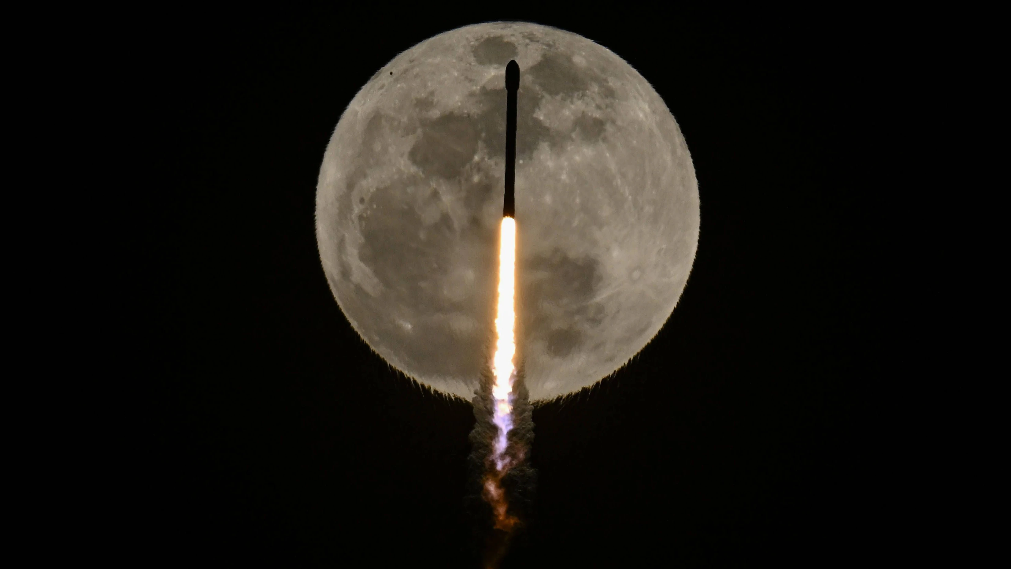Eine Falcon-9-Rakete von SpaceX fliegt am Mond vorbei, während sie am Samstag, dem 12. April 2025, vom Startkomplex 39A im Kennedy Space Center in Florida ihre Starlink-Satelliten ins All befördert.