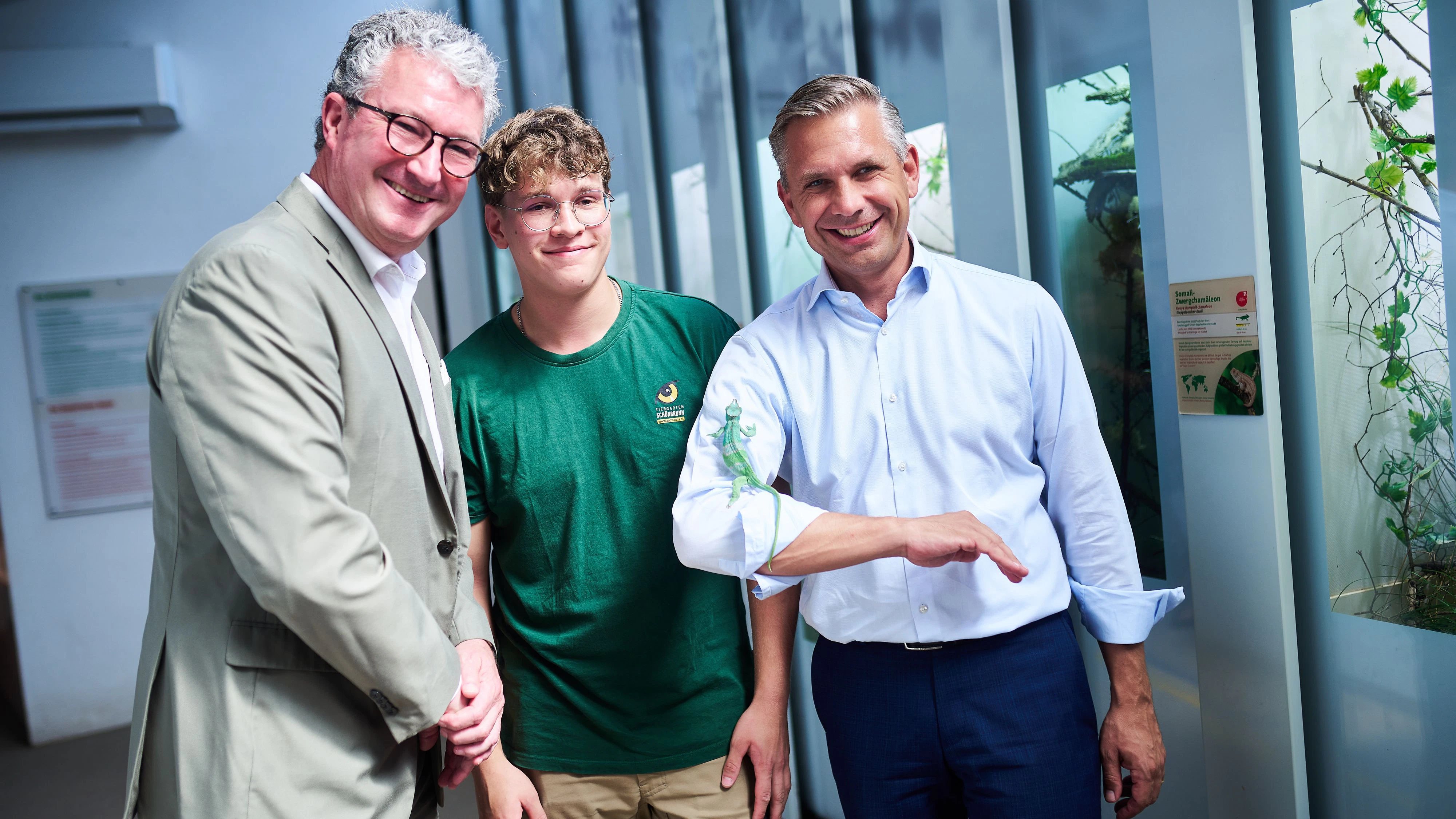 Wirtschaftsminister Hattmannsdorfer beim Besuch in Schönbrunn mit Tierpfleger-Lehrling, Tiergartendirektor Hering-Hagenbeck – und einem Chamäleon am Arm.                               