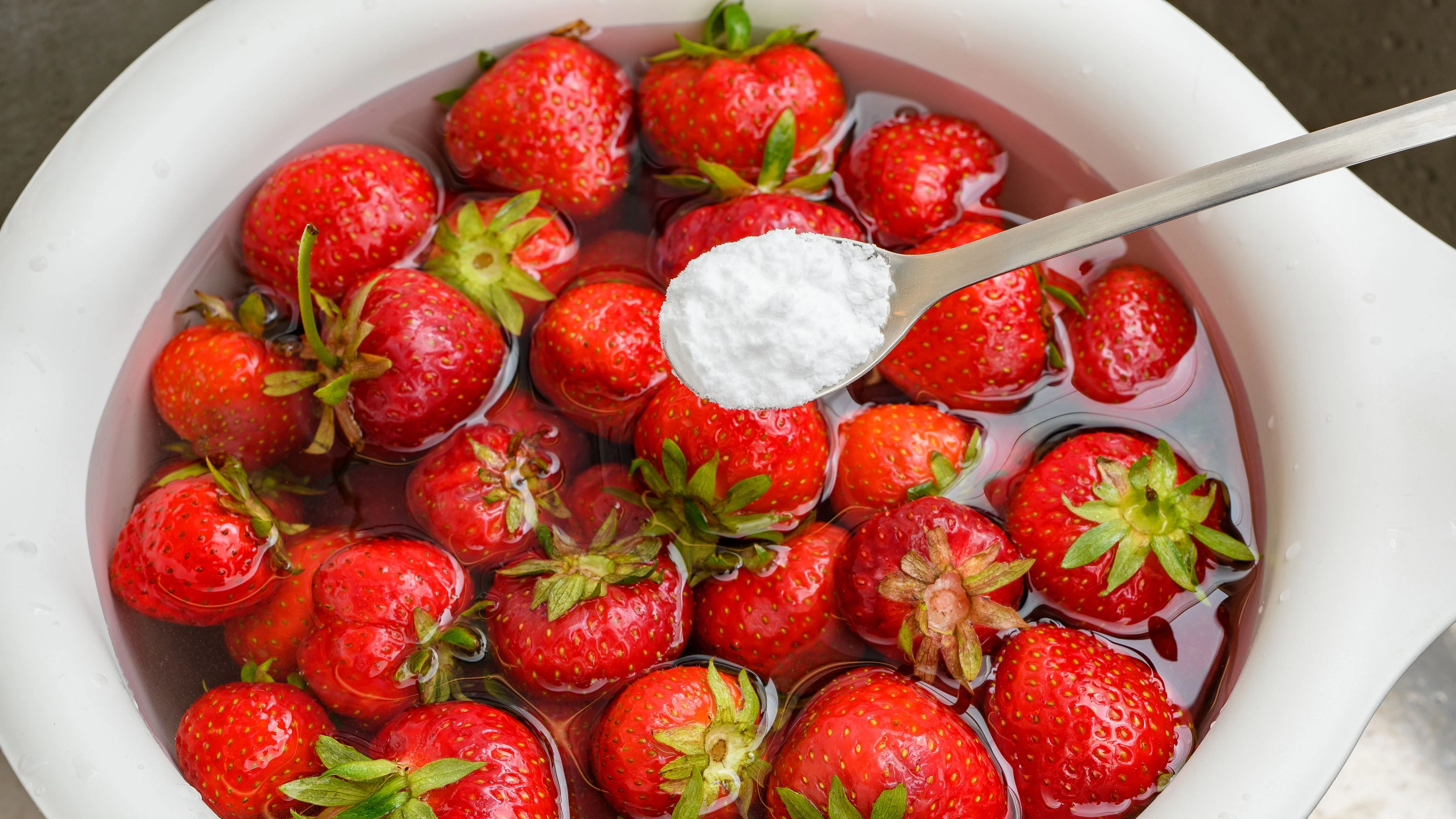 Rinsing fresh strawberry fruit in water with the addition of baking soda close-up top view
