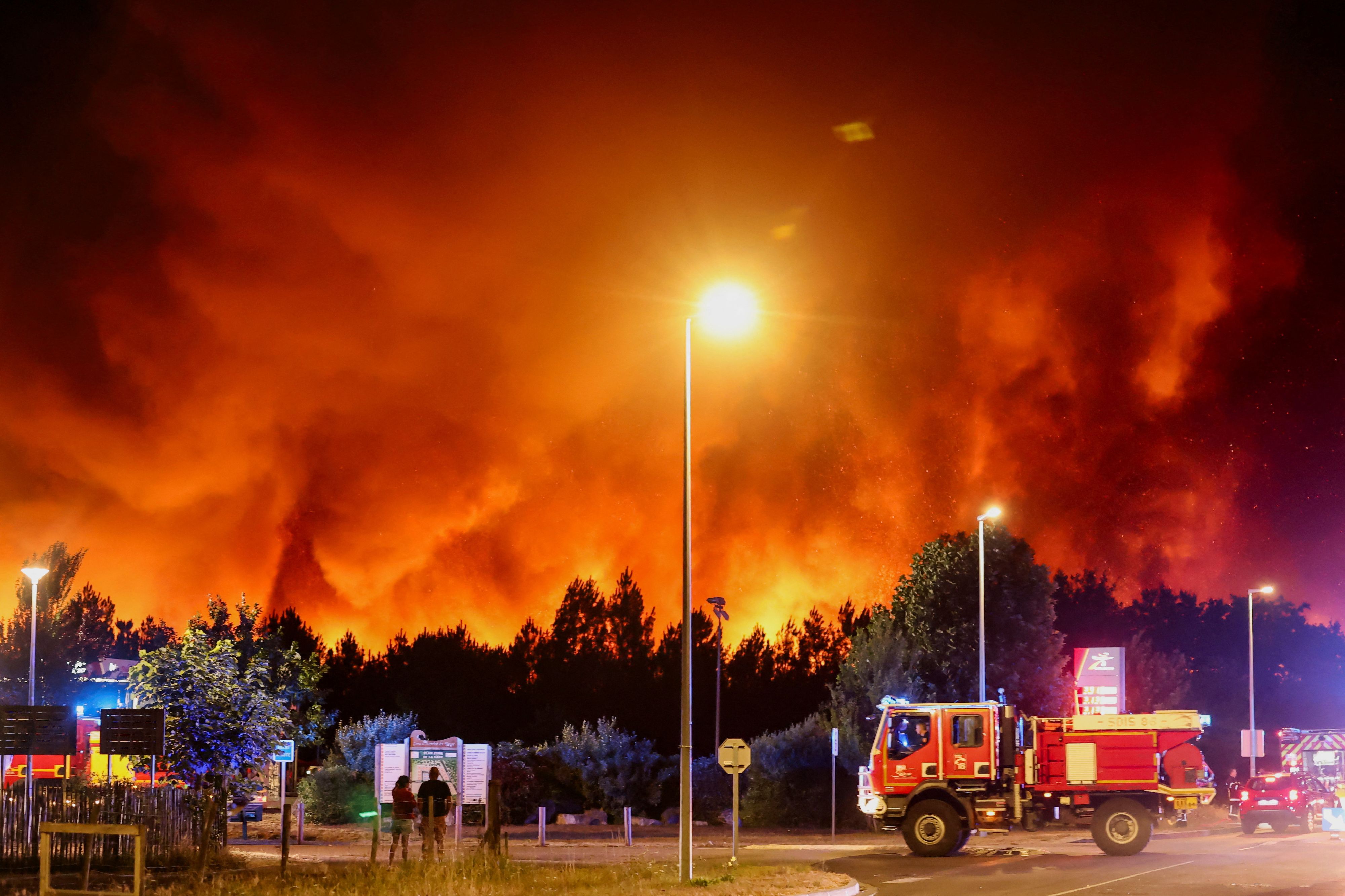 Rauch und Flammen steigen über einem Wald in Le Porge auf. 