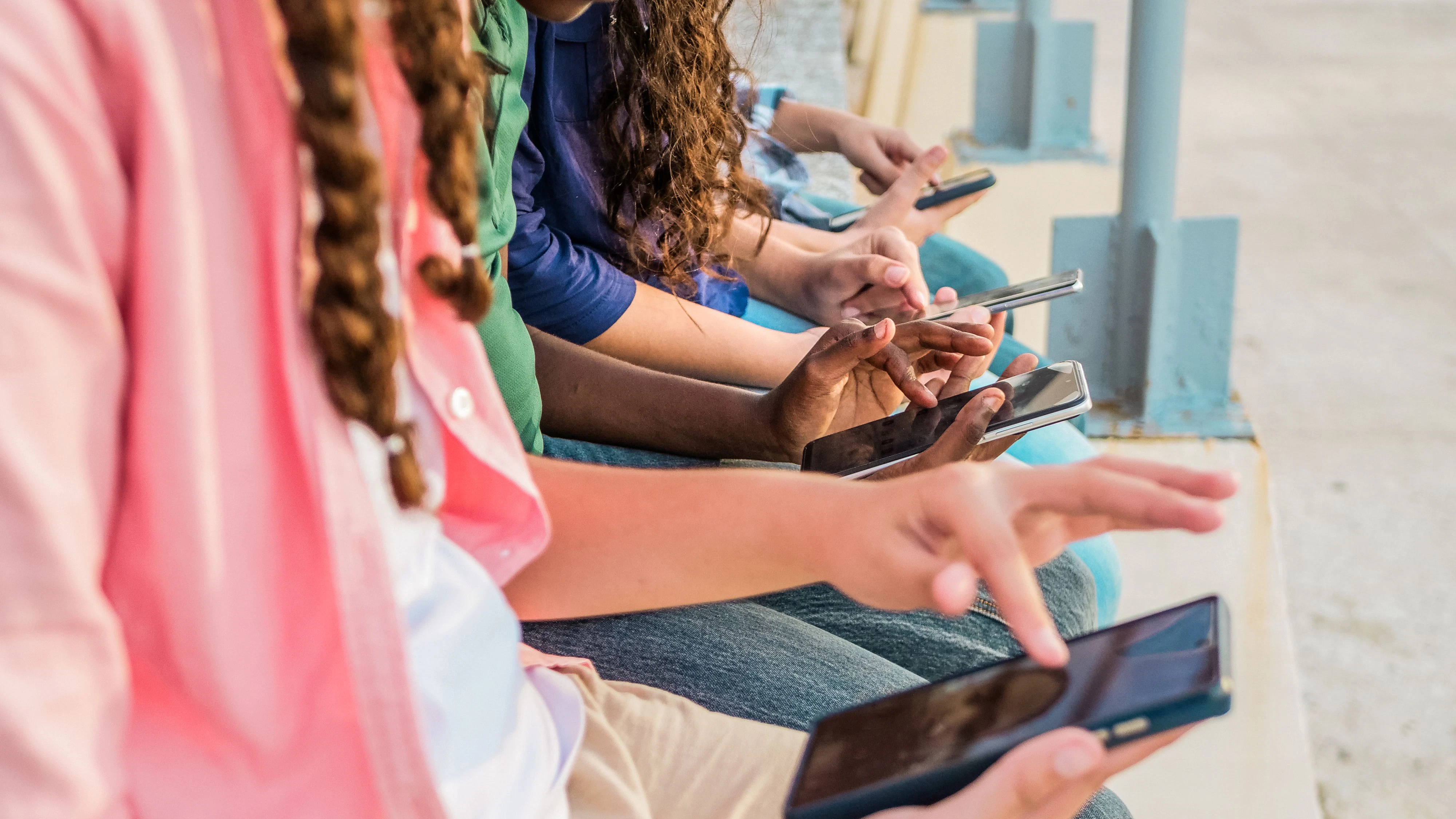 Close-up of teenage friends using mobile phone outdoors