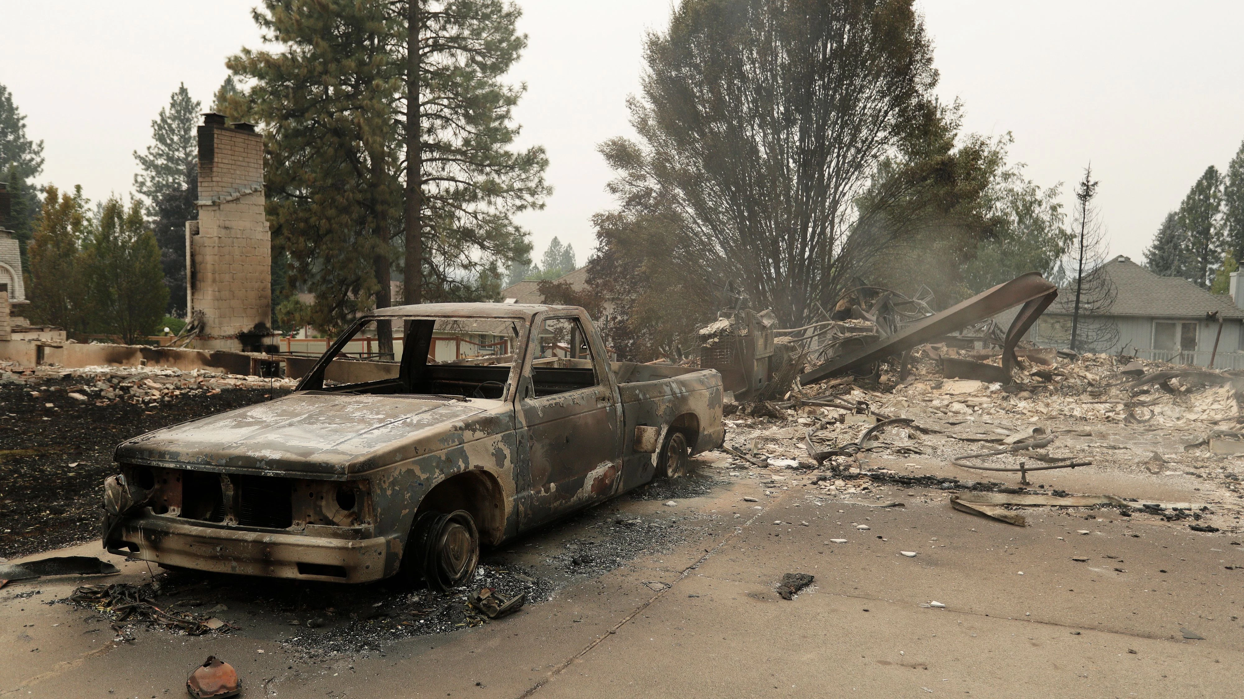 A charred vehicle and structures on N. Westgate Pl. are in ruins due to a wildfire, Sunday, Aug. 2, 2026, in Spokane, Wash. (AP Photo/Young Kwak)