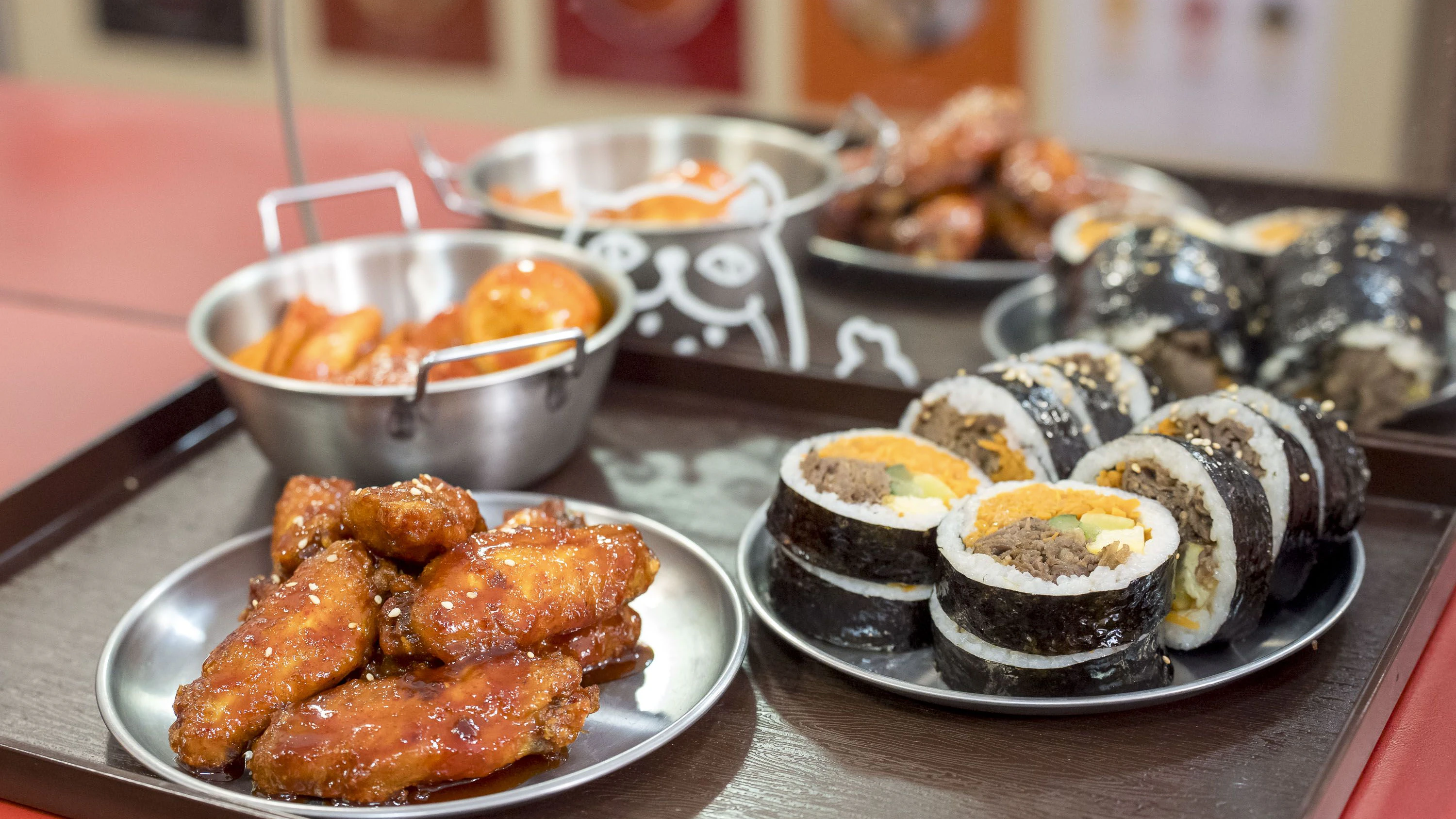 Korean Fried Chicken (vorne), Bulgogi-Gimbap (rechts) und Tteokbokki gibt es in dem kleinen Familienbistro.