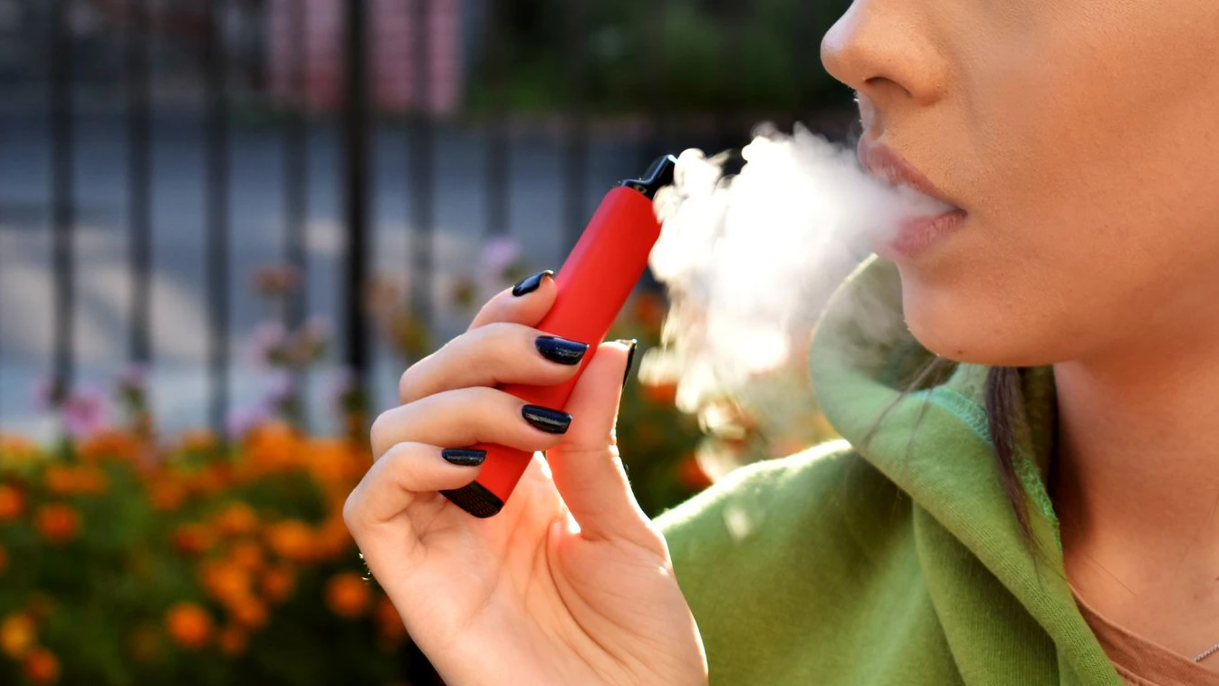 beautiful brunette smoke electronic cigarette in public places