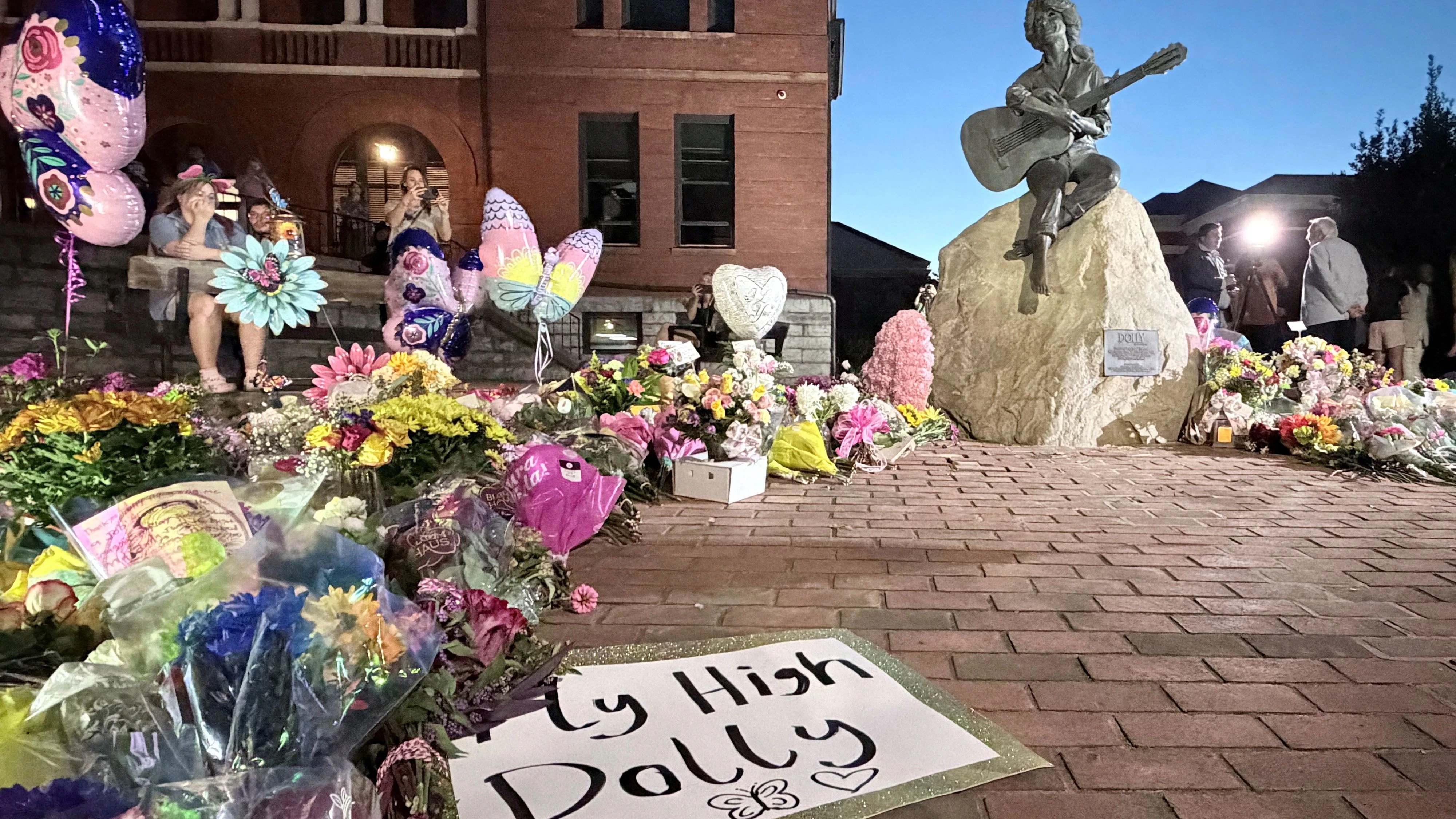 Mourners pay their respects to Dolly Parton after the announcement of her passing, at the Dolly Parton Statue in downtown Sevierville, Tennessee, U.S., August 25, 2026. Picture taken with a mobile phone. REUTERS/Kevin Fogarty 